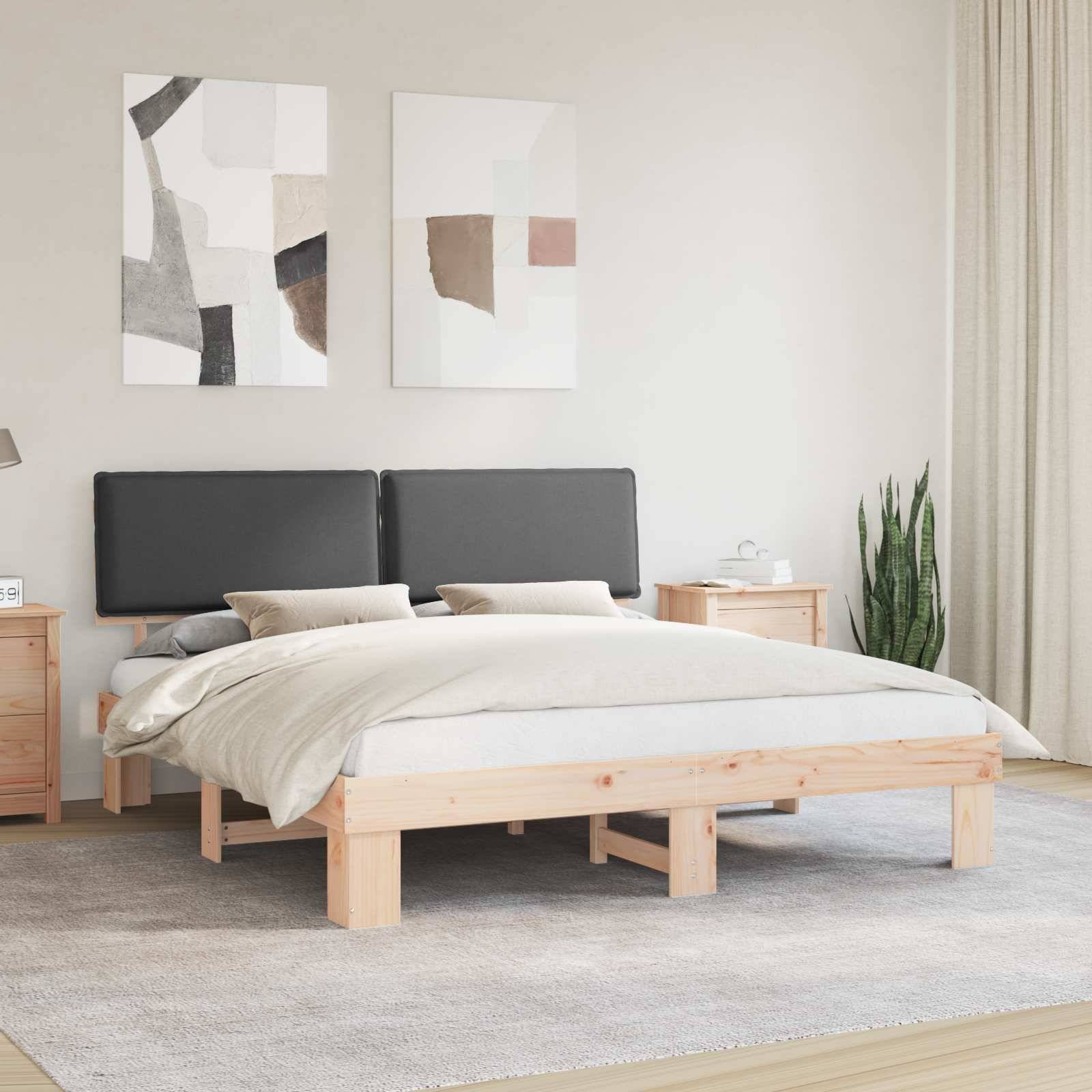 Ein minimalistisches Schlafzimmer mit einem Holzbett, grauer und beiger Bettwäsche, zwei abstrakten Kunstwerken darüber und einem hellgetönten Teppich, der den Boden bedeckt.