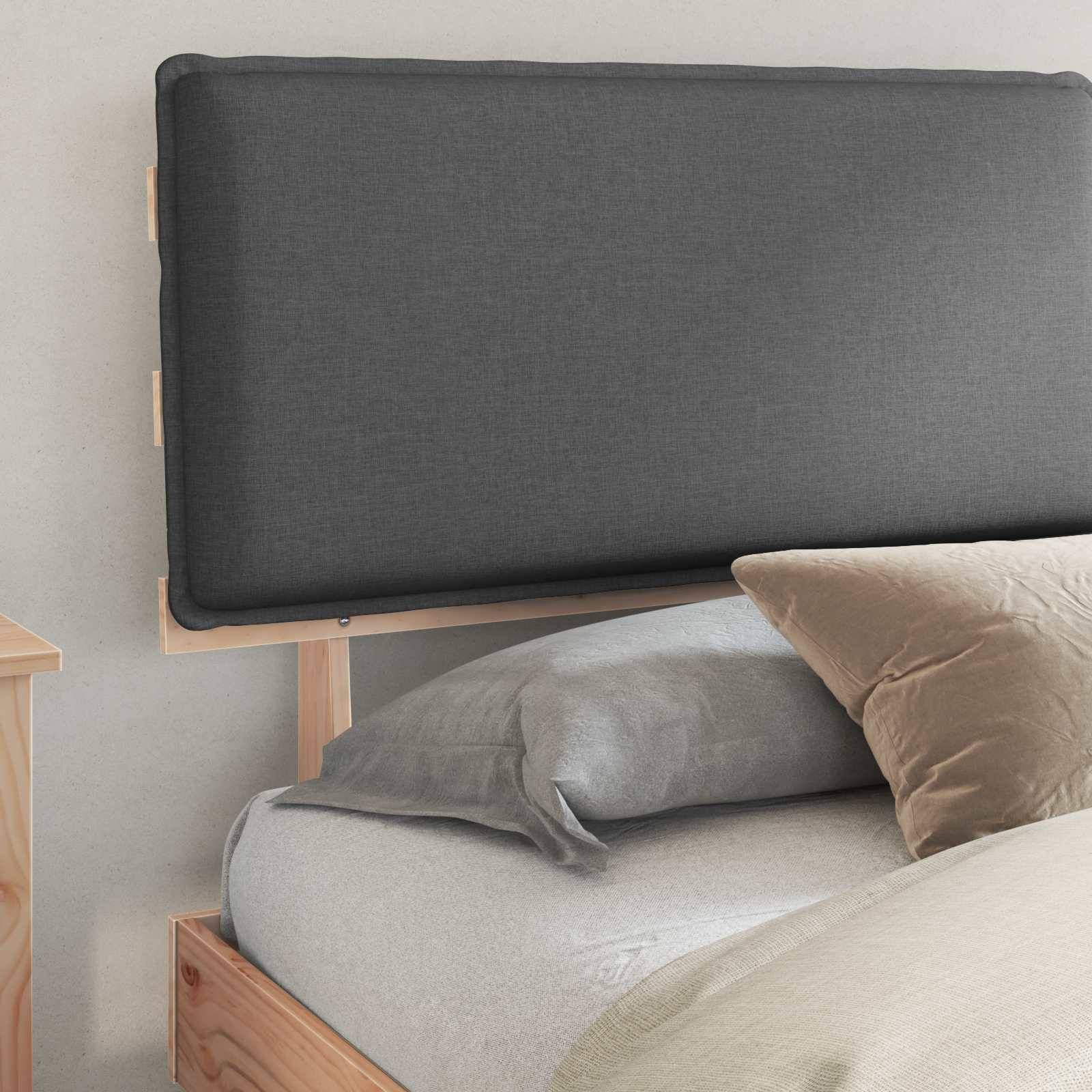 Ein ordentlich gemachtes Bett mit grauem gepolstertem Kopfteil an einer hellfarbigen Wand; ausgestattet mit zwei flauschigen Kissen und einer hellgrauen Decke.
