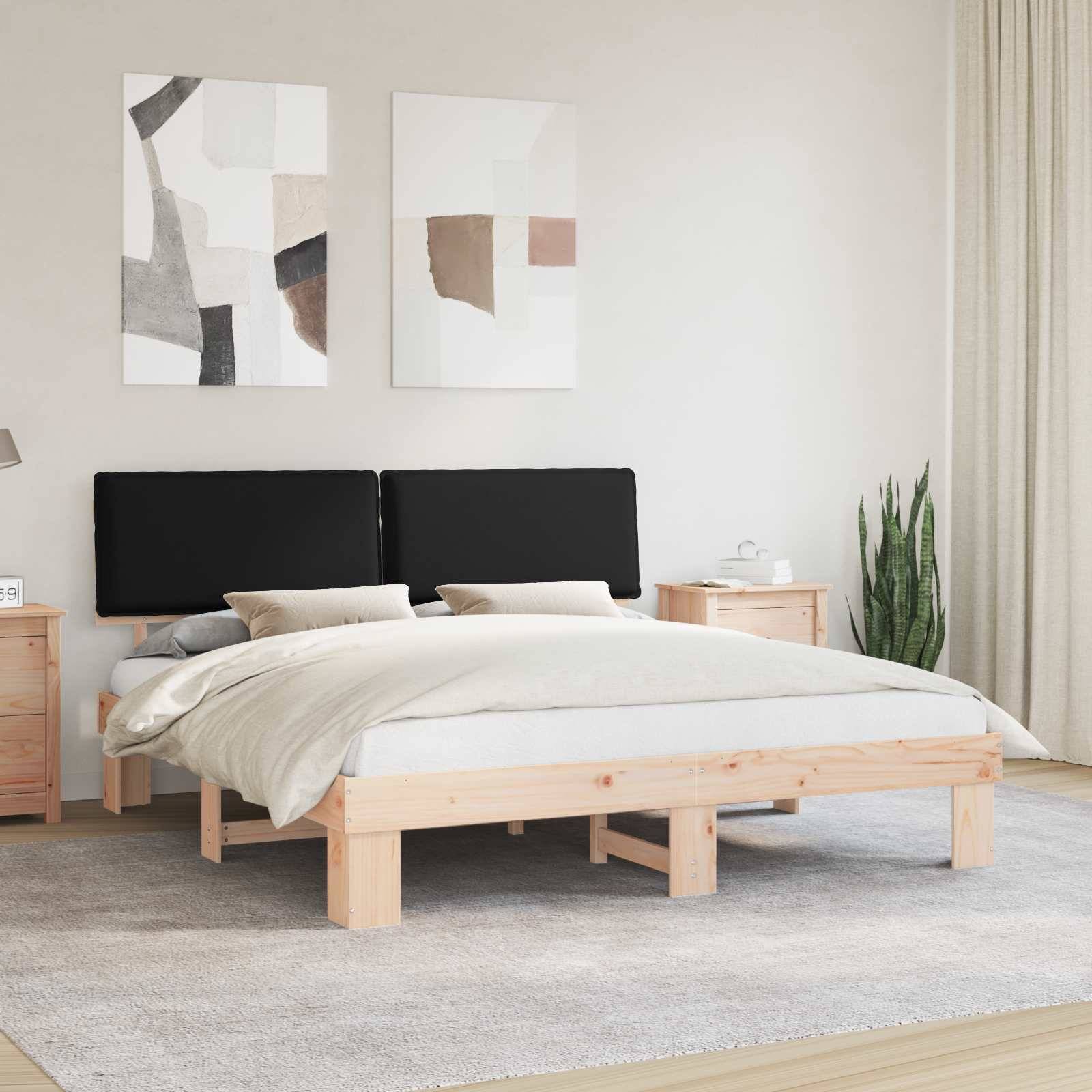 Ein minimalistisches Schlafzimmer mit einem Holzbett, schwarzem Kopfteil, grauer Bettwäsche, zwei abstrakten Gemälden an der Wand, einem Nachttisch und einer Lampe.