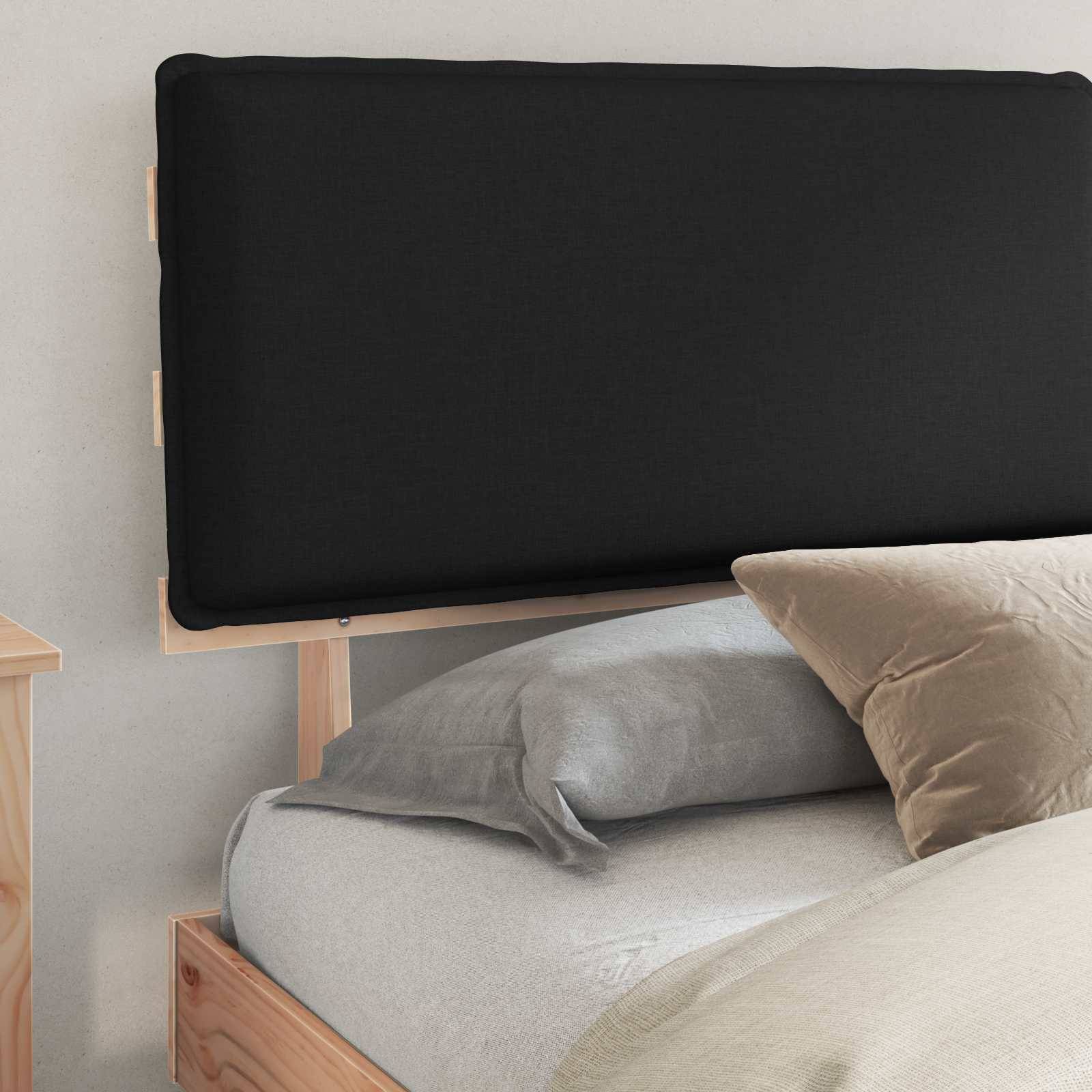 Ein minimalistisches Schlafzimmer mit einem Holzbettrahmen, grauer Bettwäsche und einem großen schwarzen rechteckigen Kopfteil an einer hellfarbi­gen Wand.