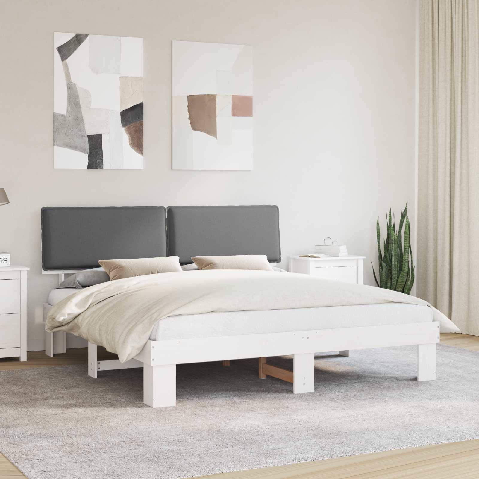 Ein modernes Schlafzimmer mit einem weißen Bett, einem grauen Kopfteil und neutraler Bettwäsche. Abstrakte Kunst hängt über dem Bett. Auf dem Nachttisch stehen eine Lampe und eine Uhr.