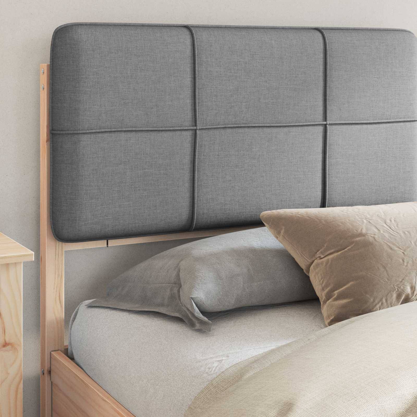 Grauer Polsterkopfteil mit Gittermuster ist an einem hellen Holzbettgestell befestigt. Ein graues Kissen und ein beiges Kissen liegen auf dem Bett.