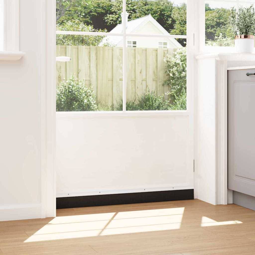 Ein sonniger Raum mit einem großen Fenster gibt den Blick auf einen Garten mit grünen Sträuchern und einer weißen Scheune frei. Im Innenraum ist ein Teil einer grauen Küchentheke sichtbar.