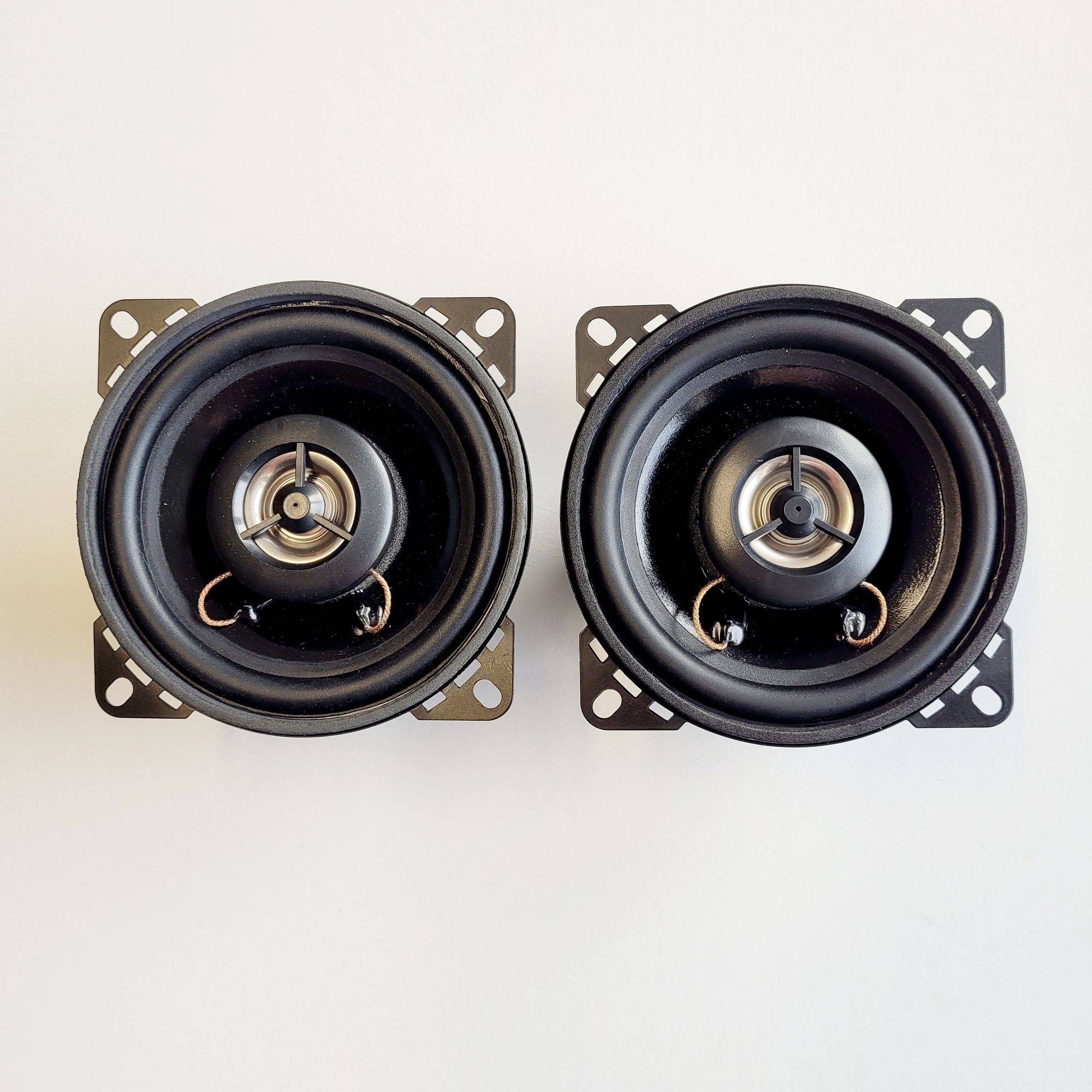 Zwei schwarze, kreisförmige Lautsprecher mit silbernen Zentren, nebeneinander vor einem weißen Hintergrund positioniert.