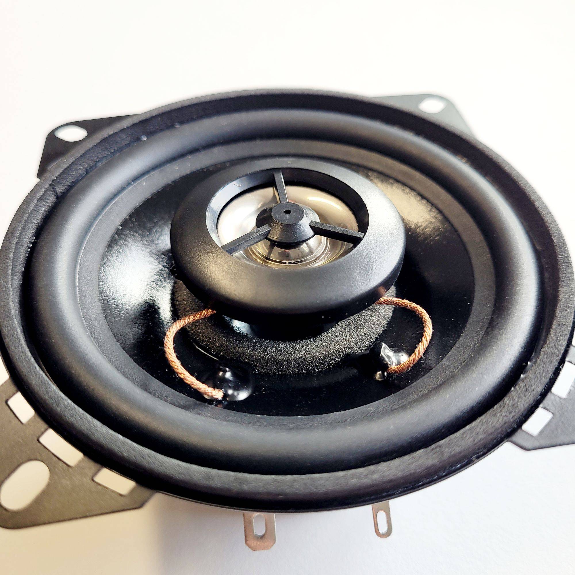 Ein Nahaufnahmebild einer kreisrunden Lautsprechermembran mit metallischem Zentrum und schwarzem Gummiring, das Details von Audioausrüstung detailliert zeigt.