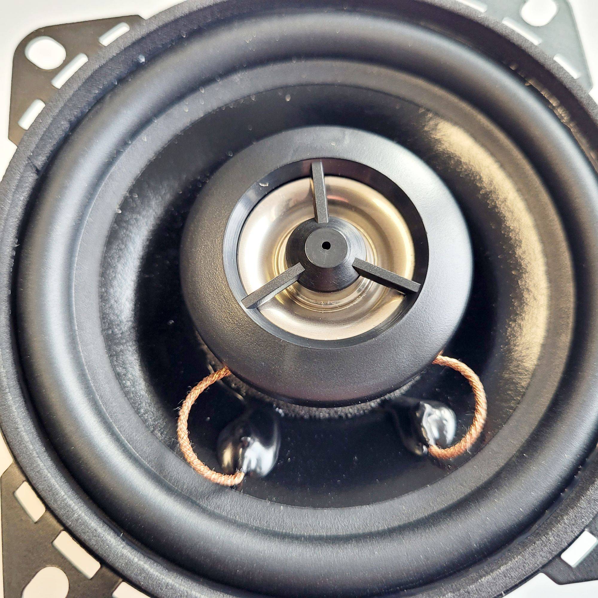 Eine Nahaufnahme einer Lautsprechermembran mit einer zentralen Staubkappe und sichtbaren Schwingspulenleitungen, die die raffinierten Details ihrer Konstruktion zeigt.