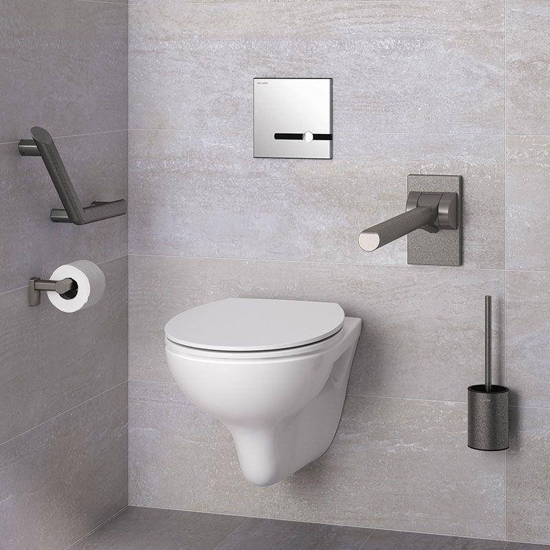Modernes, an der Wand montiertes Toilettenbecken in einem grau gefliesten Badezimmer mit Haltegriffen, Toilettenpapierhalter, Spülplatte und Toilettenbürsten-Halter