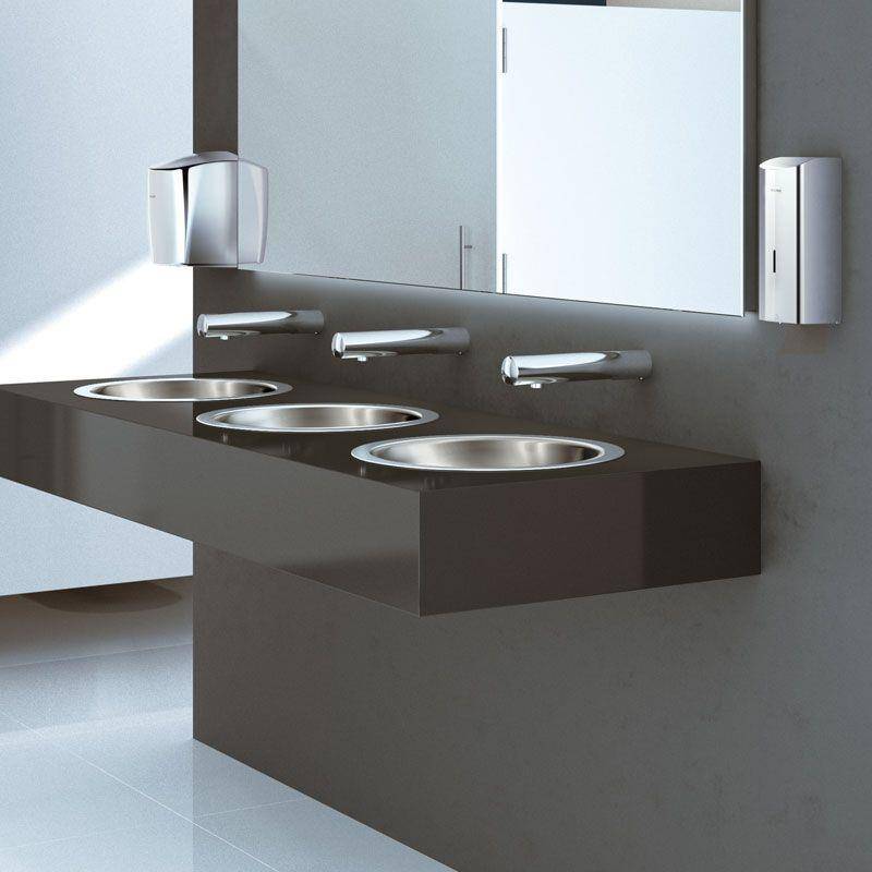 Modernes öffentliches Badezimmer mit drei Edelstahlbecken in einem dunklen schwebendem Waschtisch, wandmontierten Armaturen, Spiegeln und Seifenspendern.