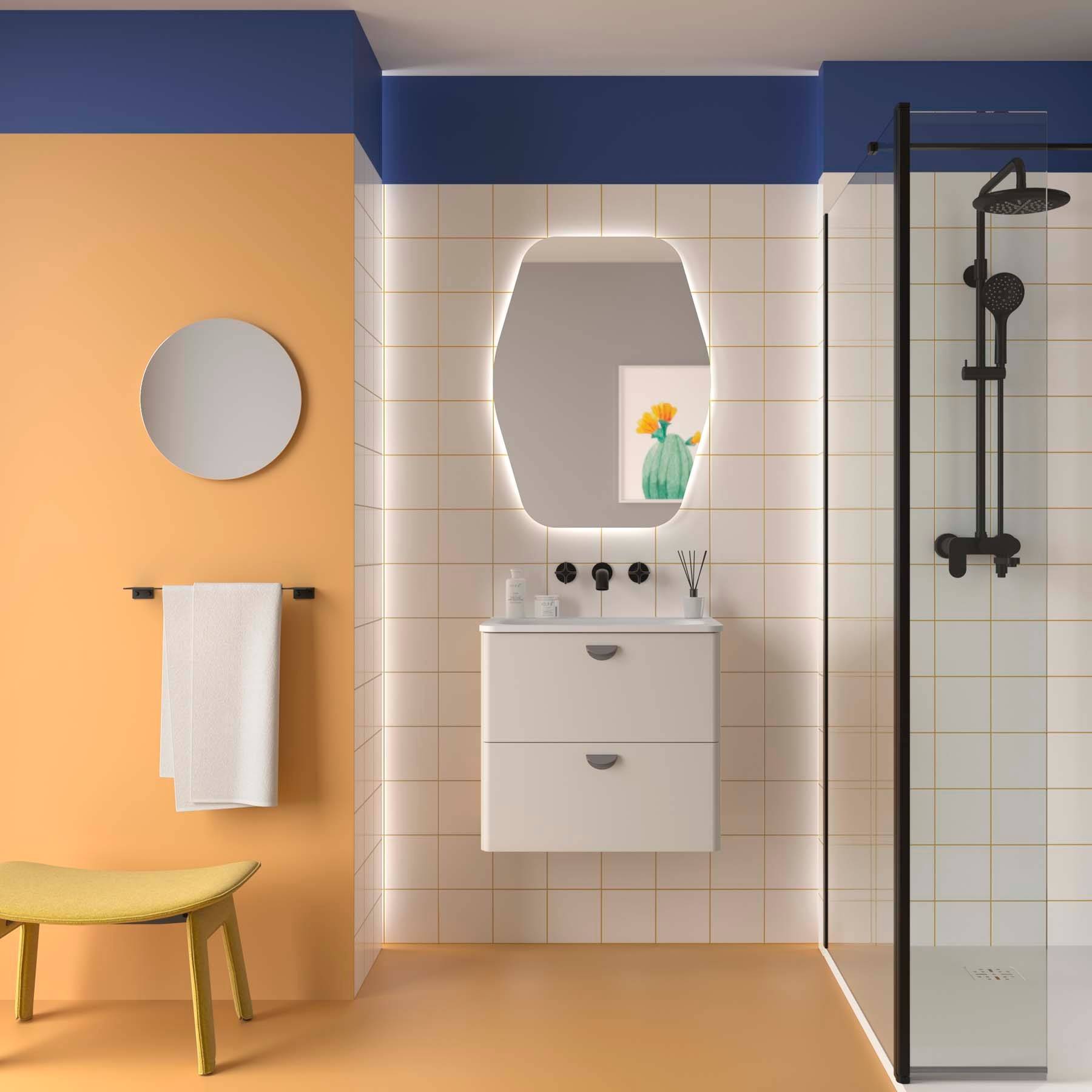 Ein modernes Badezimmer mit orange und blauen Wänden verfügt über eine Dusche mit Glasumrandung, weißem Waschtisch, rundem Spiegel und gelber Bank.