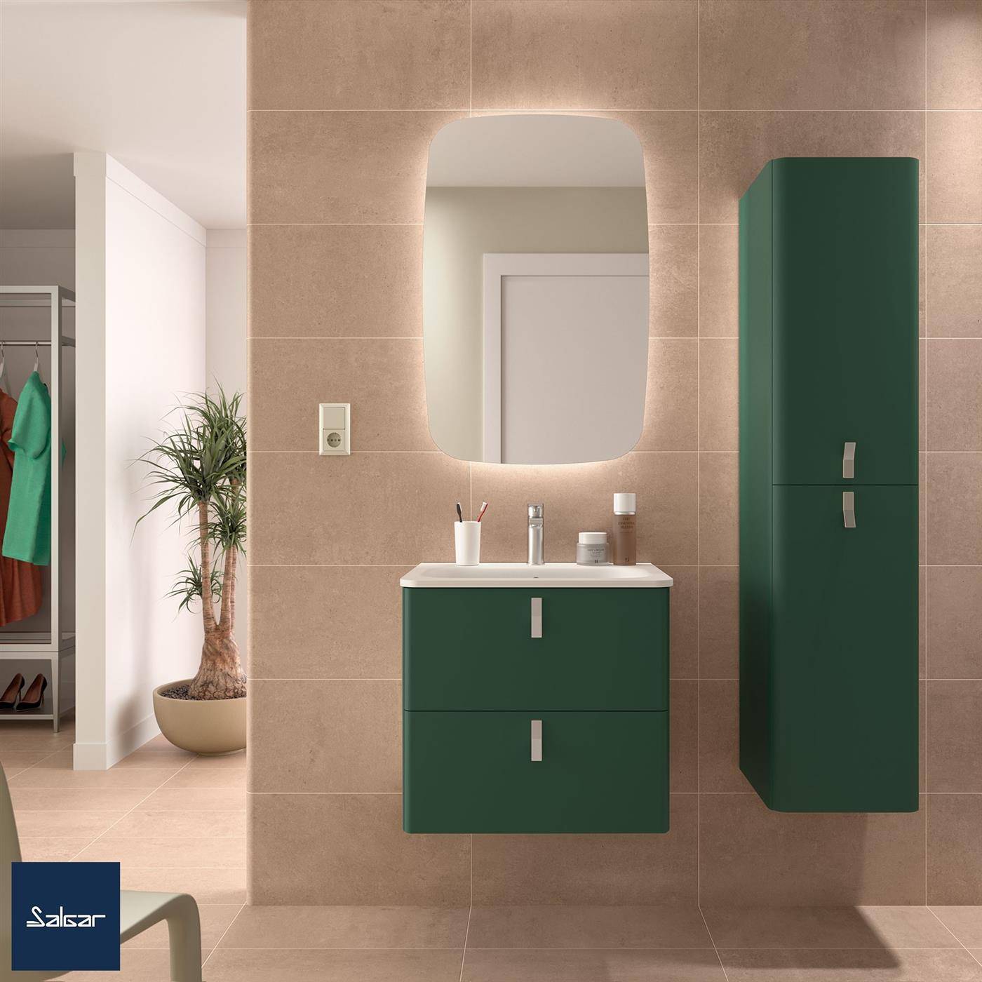 Modernes Badezimmer mit beigefarbenen Fliesen, grünem Wandwaschbecken und Schrank, beleuchtetem Spiegel, Waschbecken und einem angrenzenden offenen Kleiderschrank mit Kleidung.