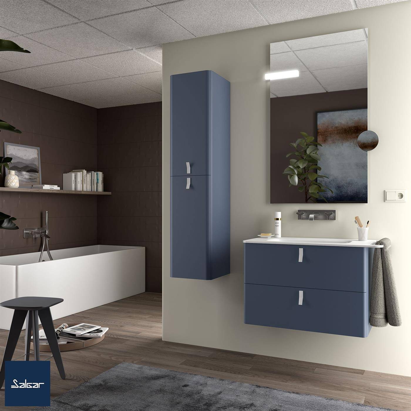Modernes Badezimmerinterieur mit dunkelblauem wandmontiertem Schrank, Waschtischunterschrank, Spiegel, Badewanne und Bodenbelag in Holzoptik.