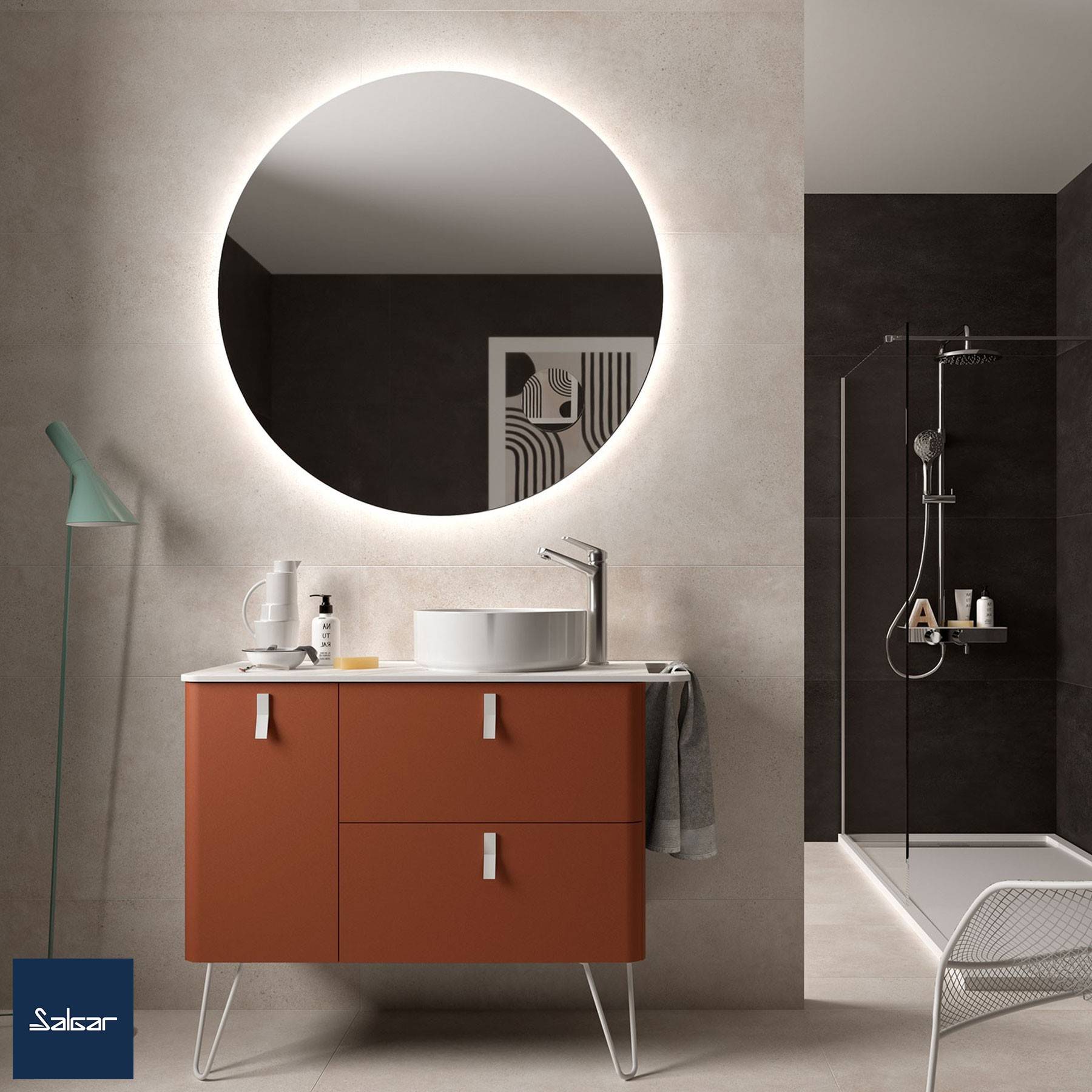 Ein modernes Badezimmer mit einem runden Spiegel, einem orangefarbenen Waschtisch mit einem weißen Waschbecken und einem minimalistischen Duschbereich mit einer Glasabtrennung.