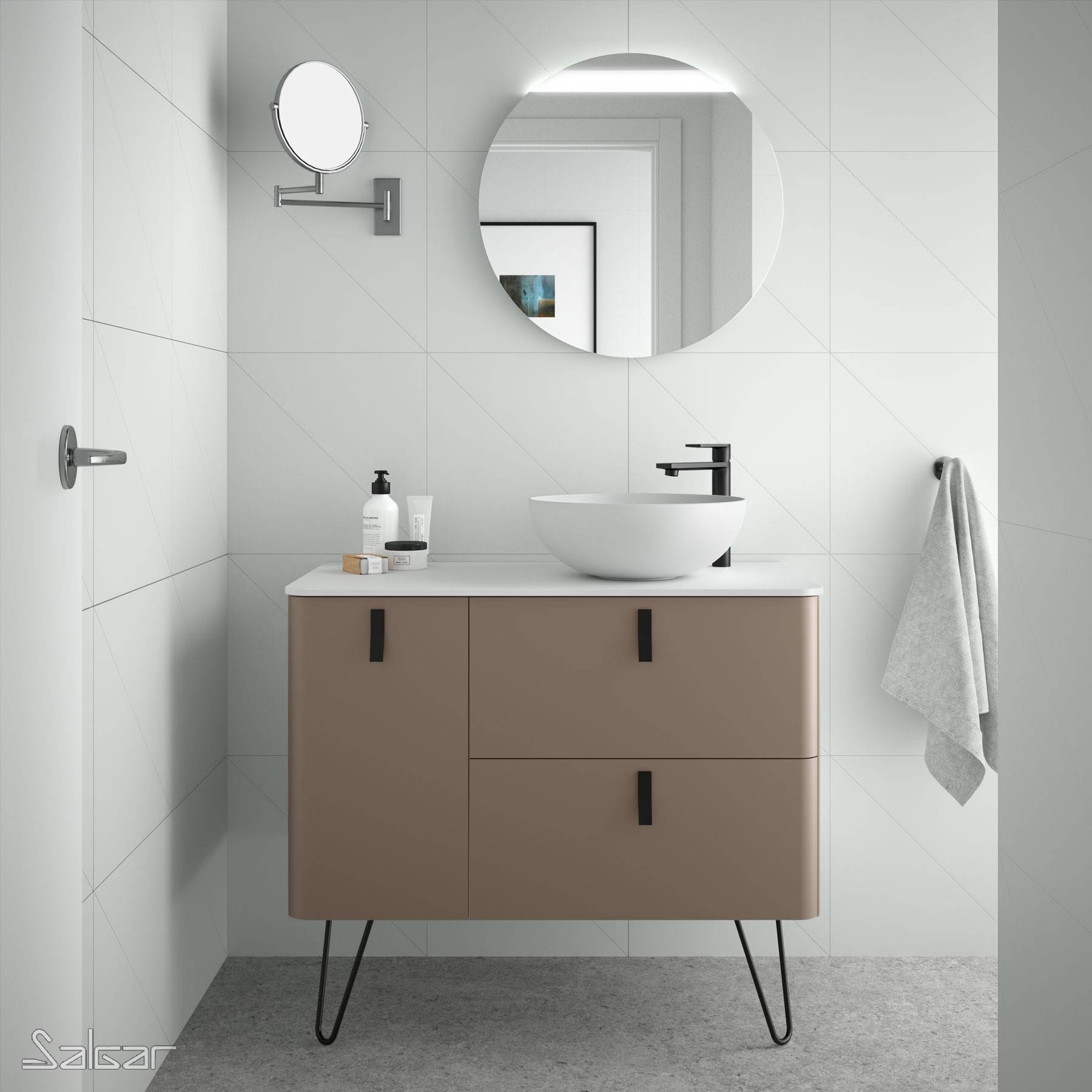 Ein modernes Badezimmer mit einem runden Spiegel, einer wandmontierter Waschbeckenarmatur und einem beigen Waschtisch mit schwarzen Griffen. Ein Handtuch hängt an einem nahegelegenen Handtuchhalter.