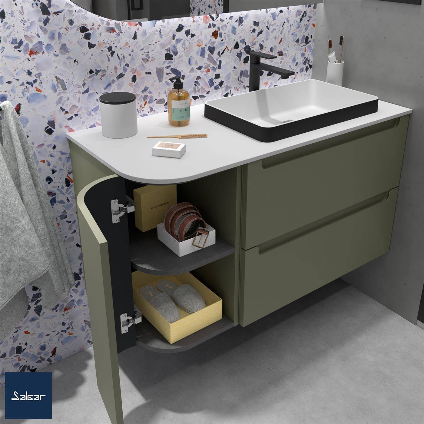 Modernes Badezimmer-Waschbecken mit mattem grünen Schränken, weißer Arbeitsplatte, schwarzem Waschbecken, offenen Regalen und Seifenzubehör vor Terrazzo-Wandfliesen.