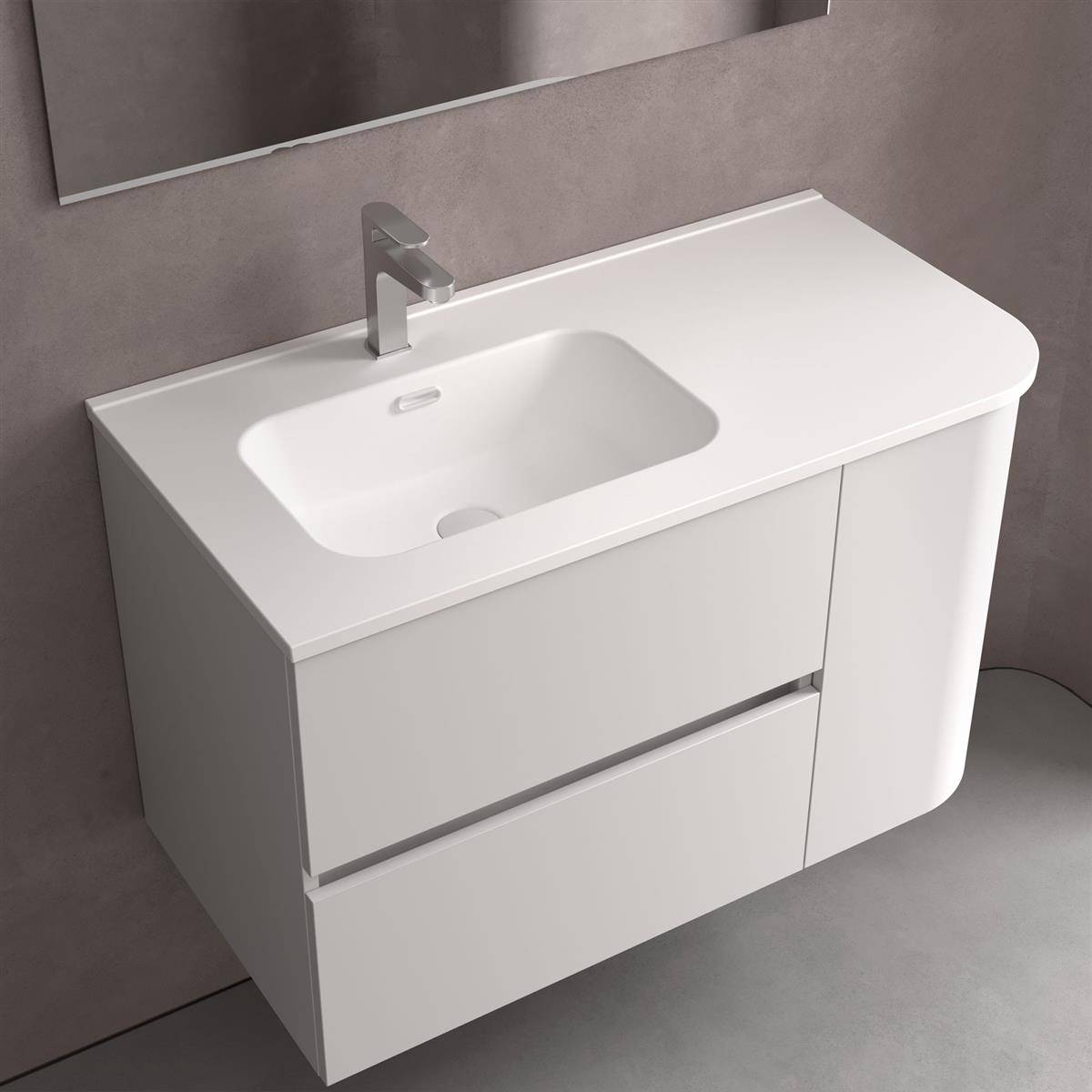 Weiße moderne Badezimmerkommode mit integriertem Waschbecken, einfachem Wasserhahn und zwei grifflosen Schubladen vor einer grauen Wand und einem grauen Boden.