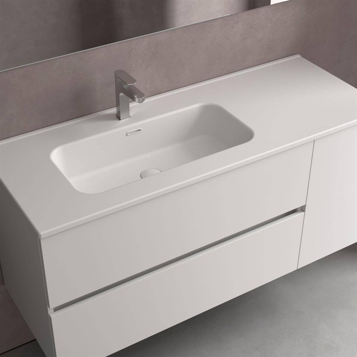 Moderne weiße Badezimmerkommode mit integriertem rechteckigen Waschbecken, einzelnem Wasserhahn und zwei grifflosen Schubladen an einer grauen Wand und auf grauem Boden.