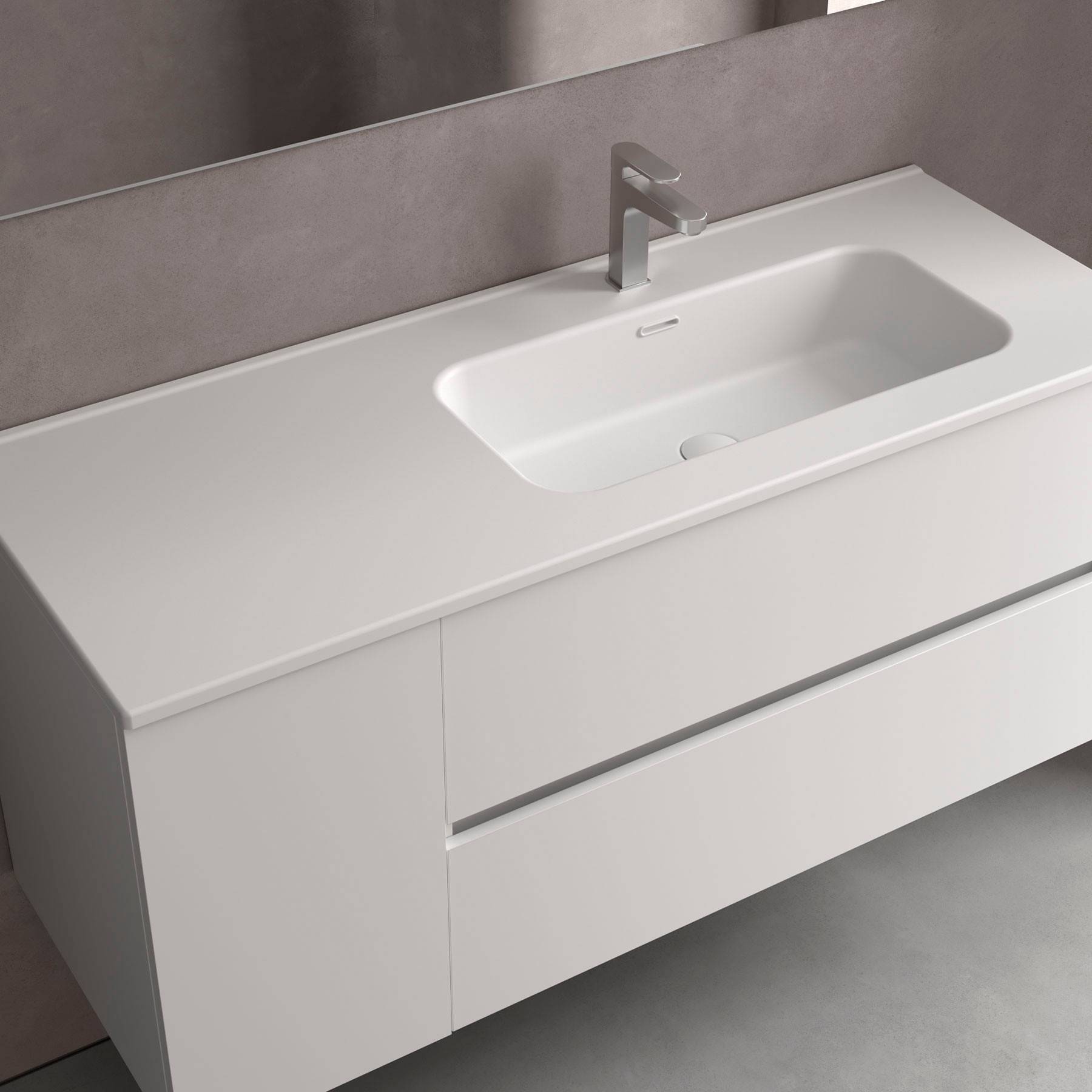 Modernes weißes Badezimmerwaschbecken mit rechteckiger Form, schlanker Arbeitsplatte und silbernem Wasserhahn, vor einer grauen Wand.