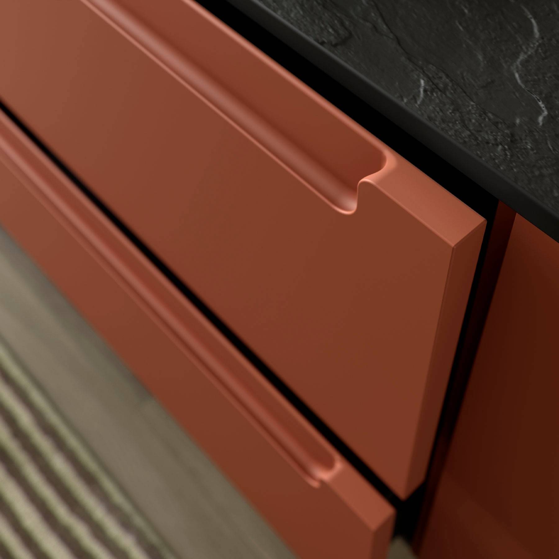 Eine Nahaufnahme eines modernen Küchenschranks mit zwei roten Schubladen und einer schwarzen Arbeitsplatte. Der Fokus liegt auf dem eleganten Design und den Griffnuten.