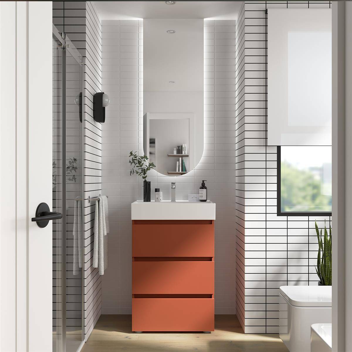 Modernes Badezimmer mit orangener Waschtischanlage, ovalem Spiegel, Glasdusche, Toilette und weißen gefliesten Wänden mit einem kleinen Fenster.