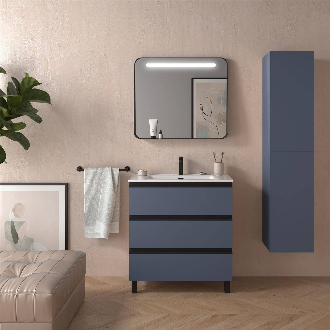Modernes Badezimmerwaschtisch mit blauen Schränken, Spiegel, Handtuchstange, Wandschrank und Waschbecken vor einer beigen Wand, mit einer gesteppten Bank und einer Pflanze auf der linken Seite.