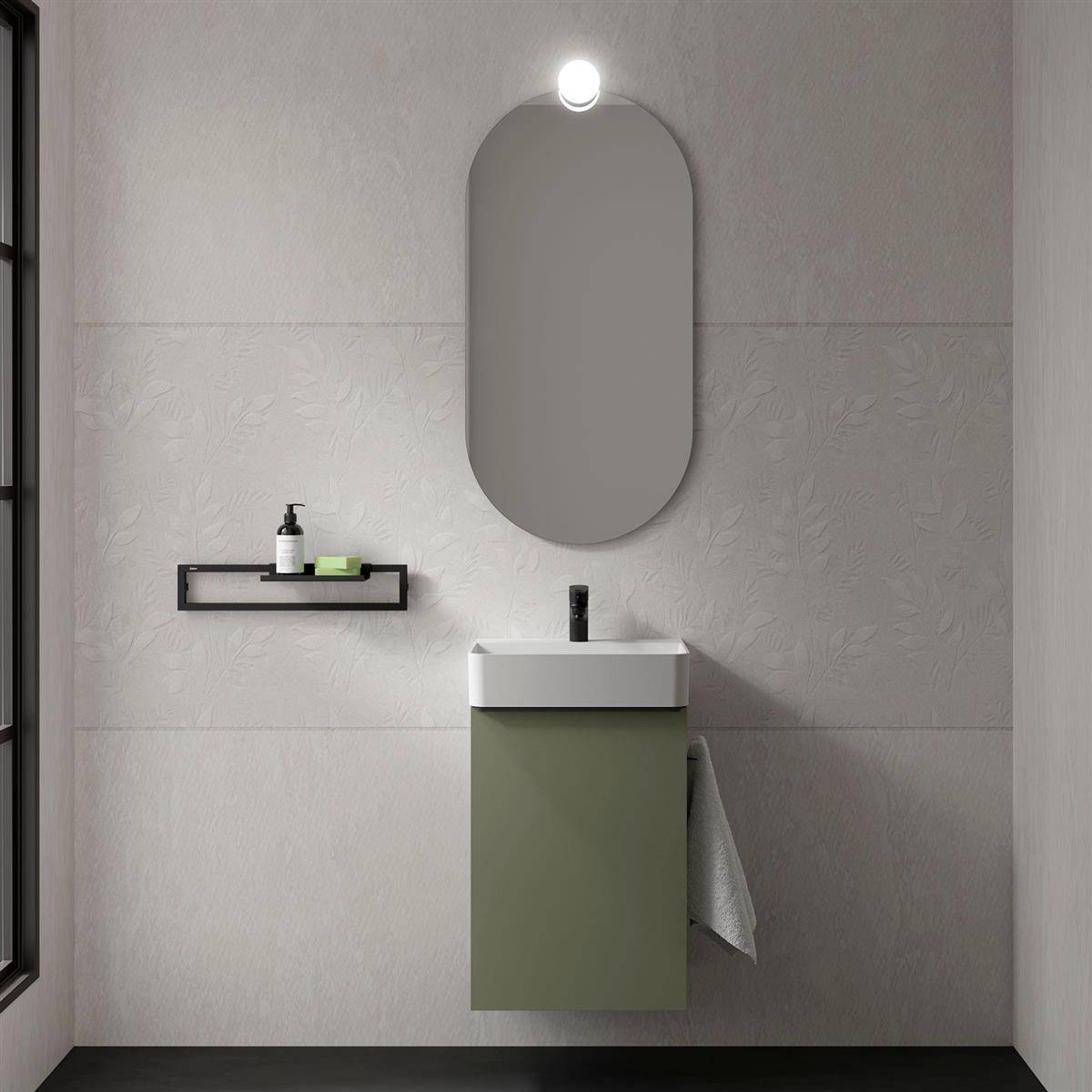 Minimales modernes Badezimmer mit olivegrünem Waschtisch, ovalem Spiegel, Wandleuchte, Handtuch und kleinem Regal mit Seifenspender und Toilettenartikeln.