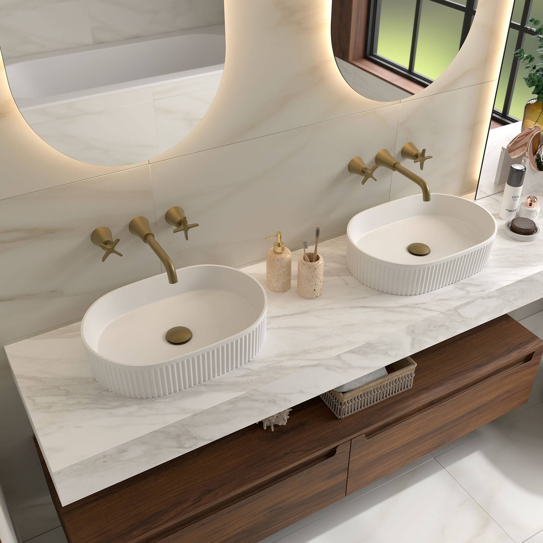 Ein modernes Badezimmer verfügt über einen Waschtisch mit Doppelwaschbecken mit weißen Becken, goldenen Armaturen und einem großen, geschwungenen Spiegel. Die Dekoration ist minimalistisch mit erdigen Tönen.