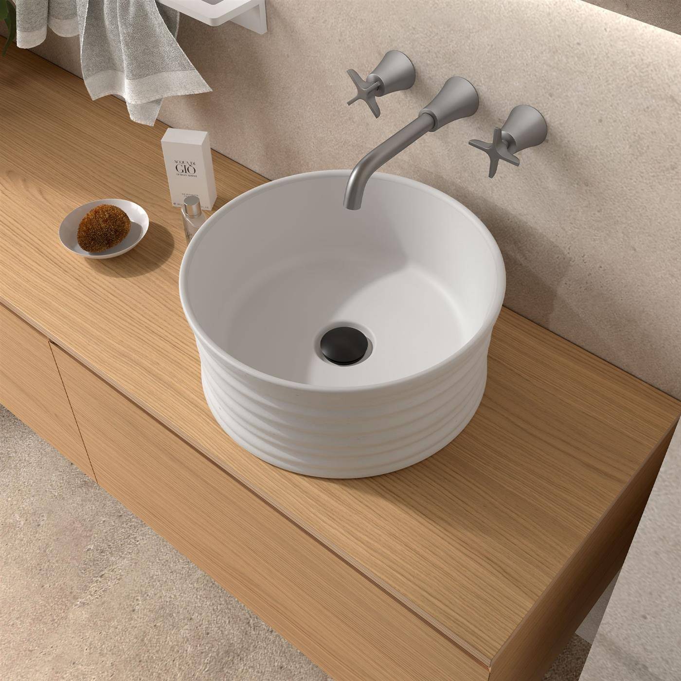 Modernes Badezimmerwaschtisch mit einer runden weißen Aufsatzschale, wandmontiertem Wasserhahn und Holzarbeitsplatte neben einer kleinen Seifenschale.