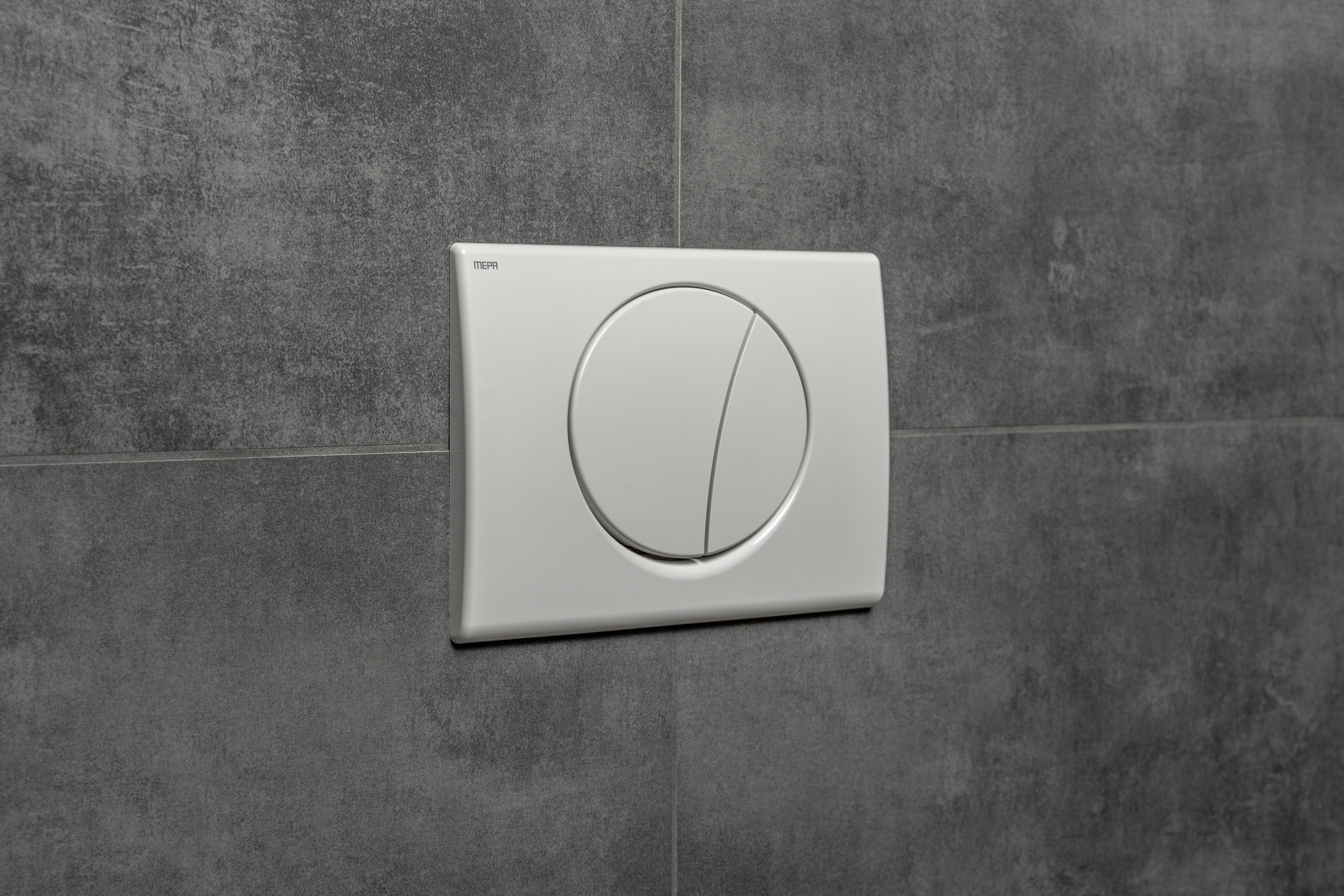 Eine moderne, wandmontierte Betätigungsplatte für einen Dual-Flush-Toilettenspülung mit zwei Tasten für unterschiedliche Wassermenge, vor einer grauen gefliesten Wand.