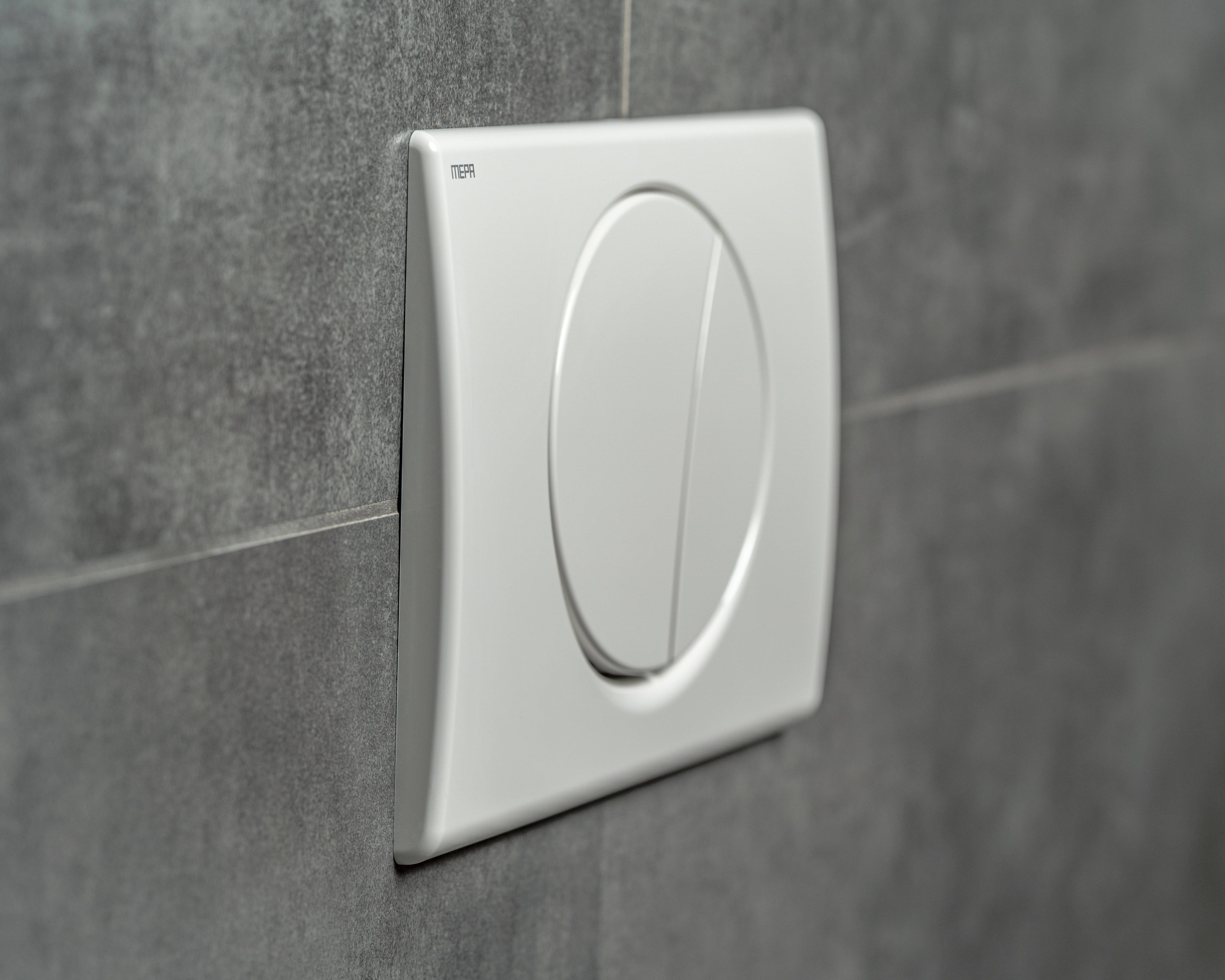 Bündig eingebaute Zwei-Mengen-Spülknöpfe an einer grauen Fliesenwand, mit zwei separaten Tasten zur Steuerung der Spülmenge in einer Toilettenumgebung.