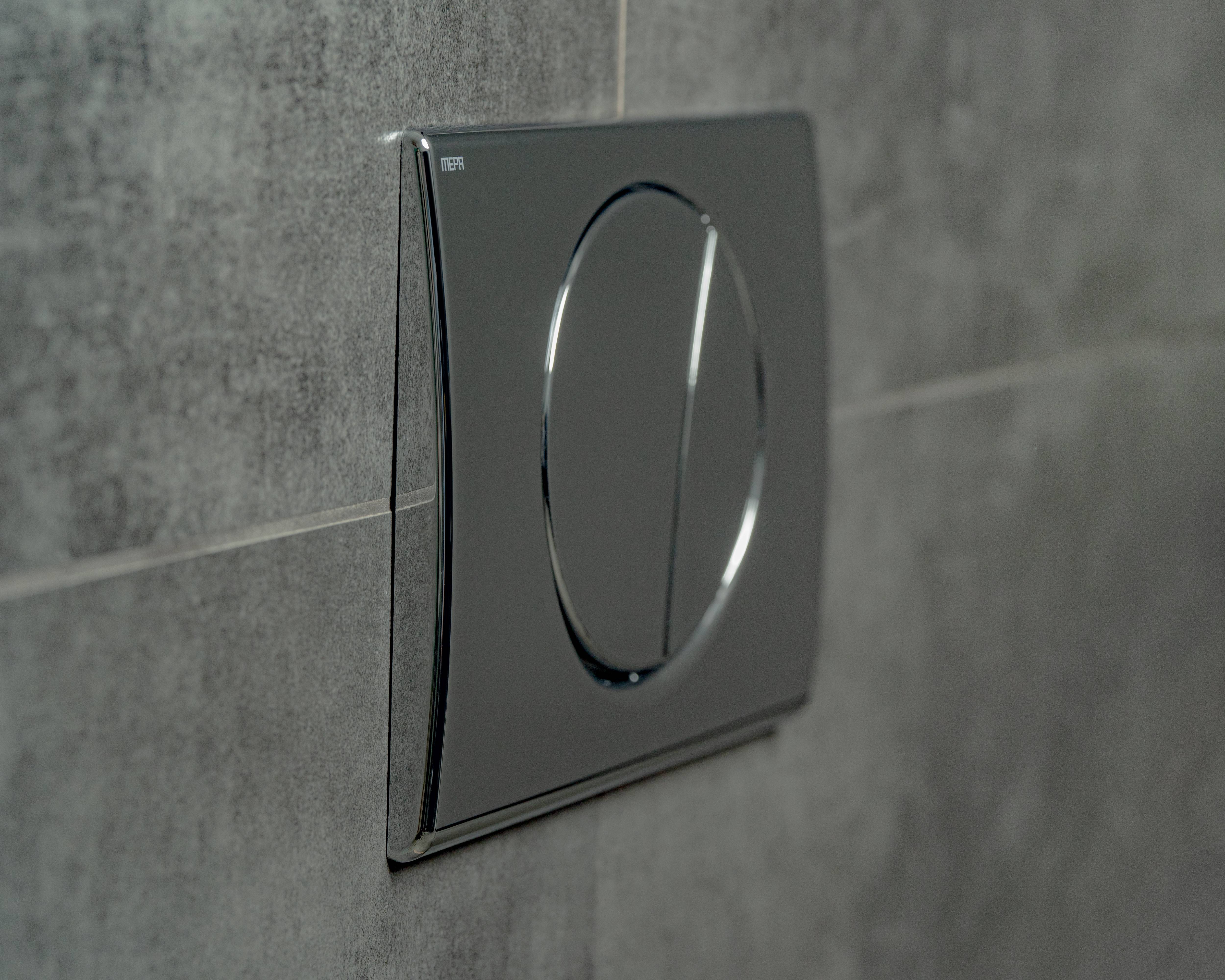 Eine elegante, moderne Betätigungsplatte mit zwei Tasten ist an einer grauen gefliesten Wand montiert und deutet auf ein Zwei-Mengen-Spülsystem hin.