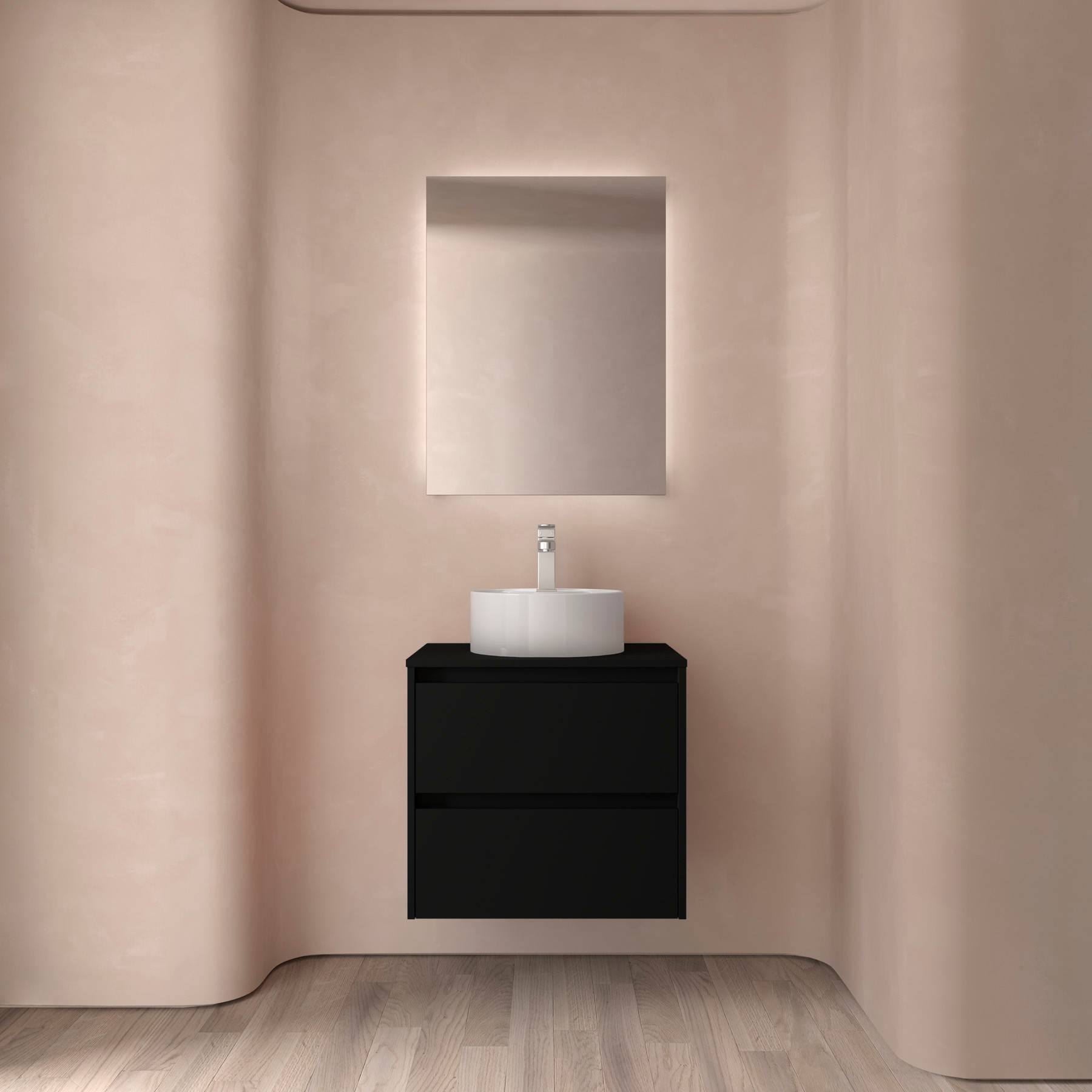 Ein minimalistisches Badezimmer mit einem schwarzen Waschtisch und einem weißen runden Waschbecken, vor einer rosa Wand. Ein großer rechteckiger Spiegel hängt darüber.