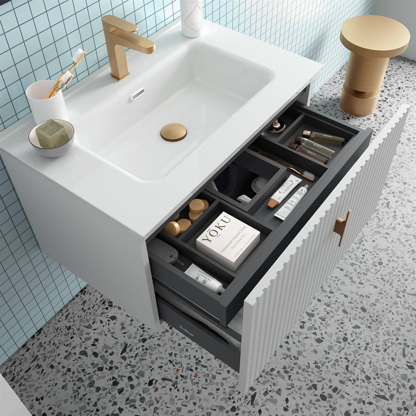 Modernes Badezimmerwaschtisch mit offenen Schubladen-Organizer und Toilettenartikeln neben einem weißen Waschbecken und goldenem Wasserhahn in einem gefliesten Badezimmer mit Terrazzoböden.