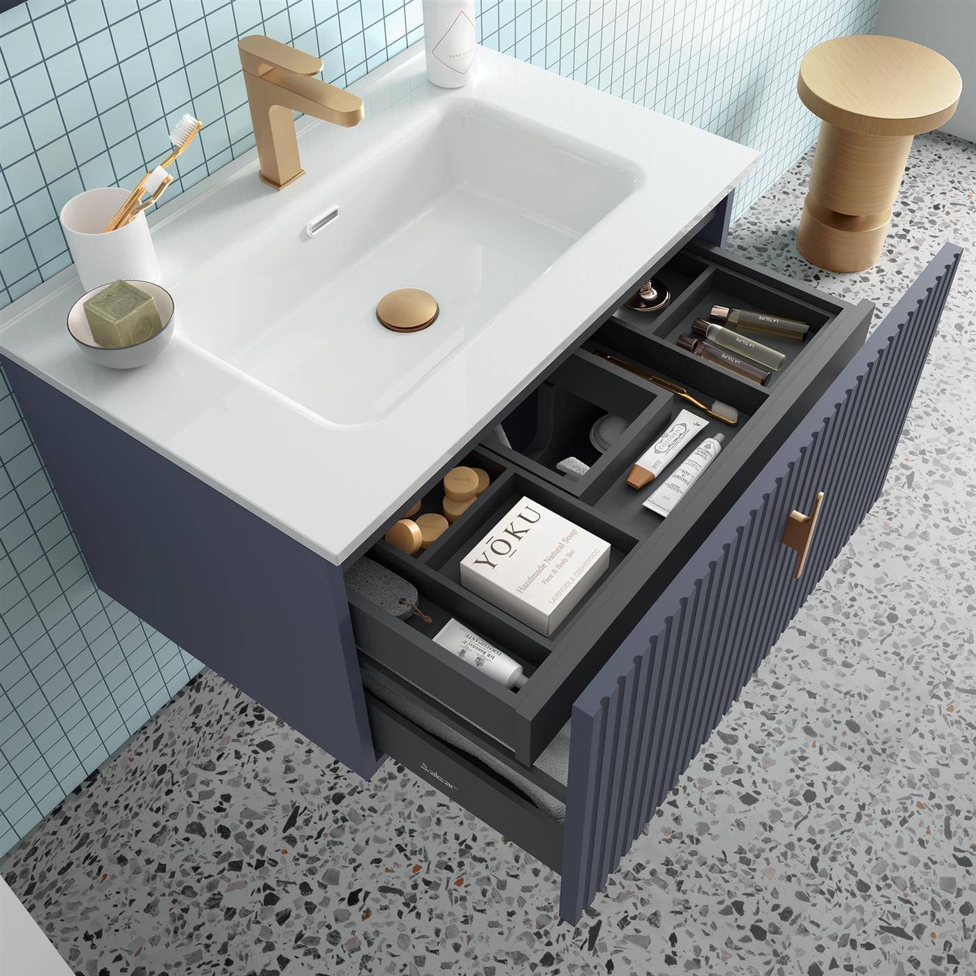 Modernes Badezimmermöbel mit weißem Waschbecken und goldenem Wasserhahn; die Schublade ist offen und zeigt ordentlich angeordnete Toilettenartikel und Kosmetikprodukte.
