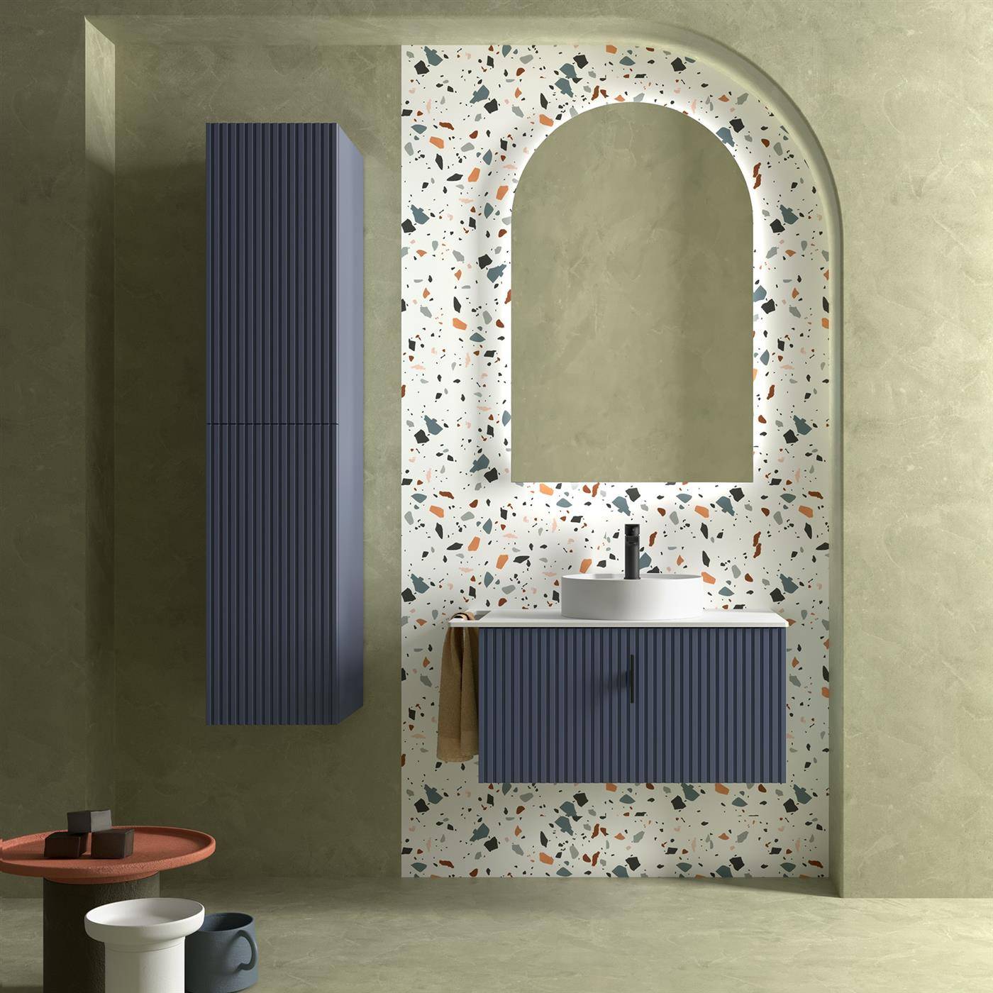 Modernes Badezimmer-Waschtisch mit geflecktem Terrazzo-Hintergrund, gewölbtem Spiegel, blauem geripptem Schrank und Wandschrank vor gedämpften grünen Wänden.