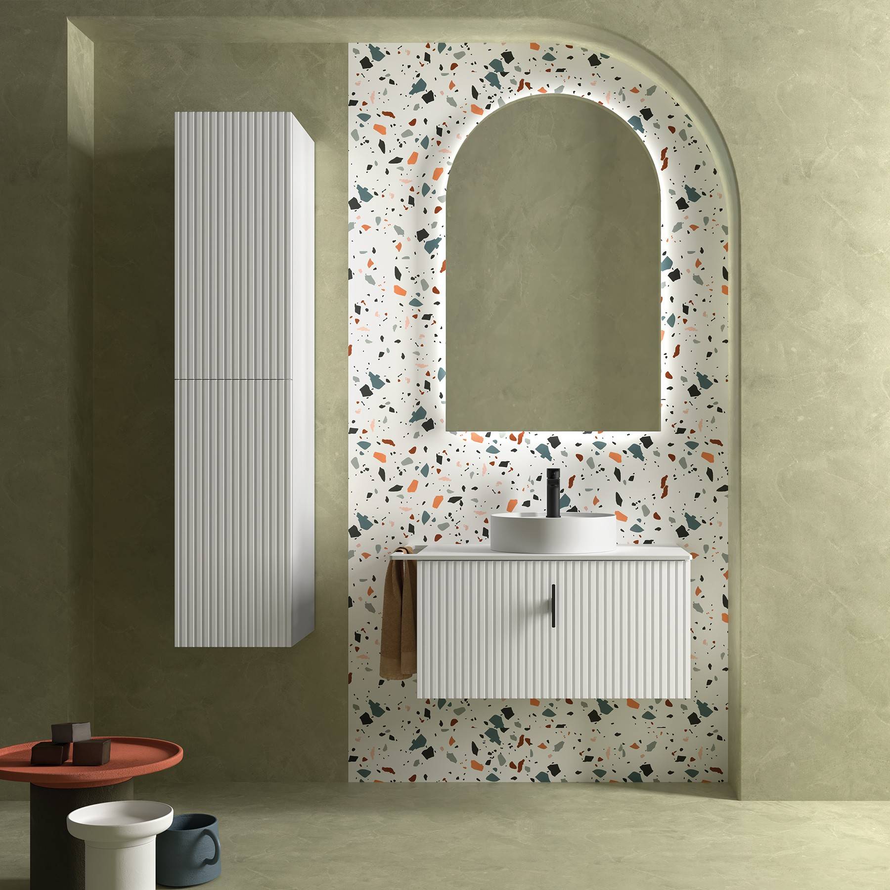 Modernes Badezimmer mit Terrazzofliesen, rundem Spiegel, weißem Schrank und Waschbecken. Minimalistisches Design mit hellgrünen Wänden und rotem Tisch.