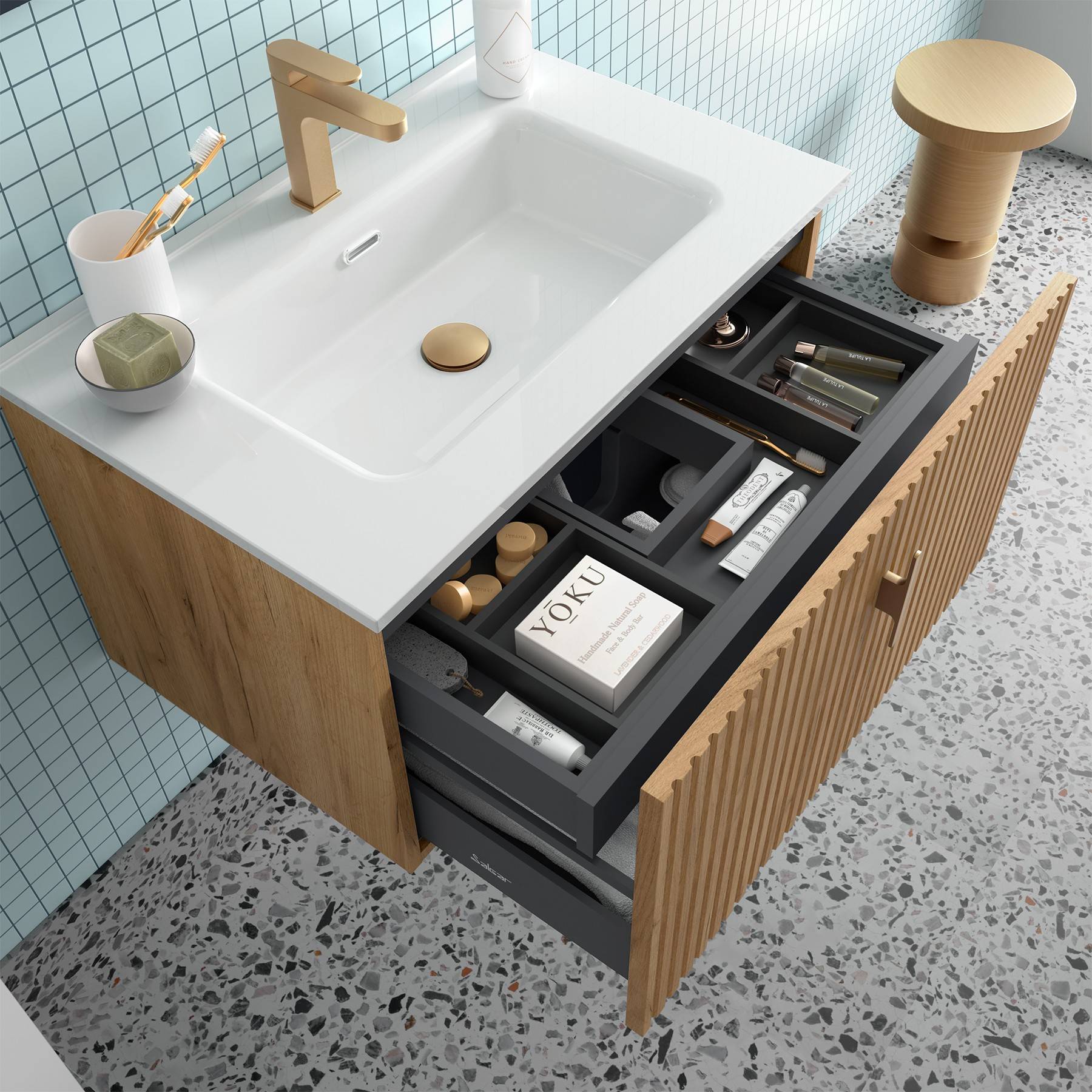 Ein modernes Badezimmer-Waschtisch mit einer offenen Schublade, die übersichtlich angeordnete Fächer mit Hautpflegeprodukten und einem 'YOKU' Buch zeigt.