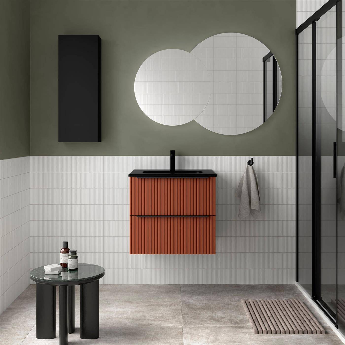 Modernes Badezimmer mit schwarzem Waschtisch und Spiegel darüber, rundem Beistelltisch, Glasschiebetür und Handtuch an der gekachelten Wand hängend.