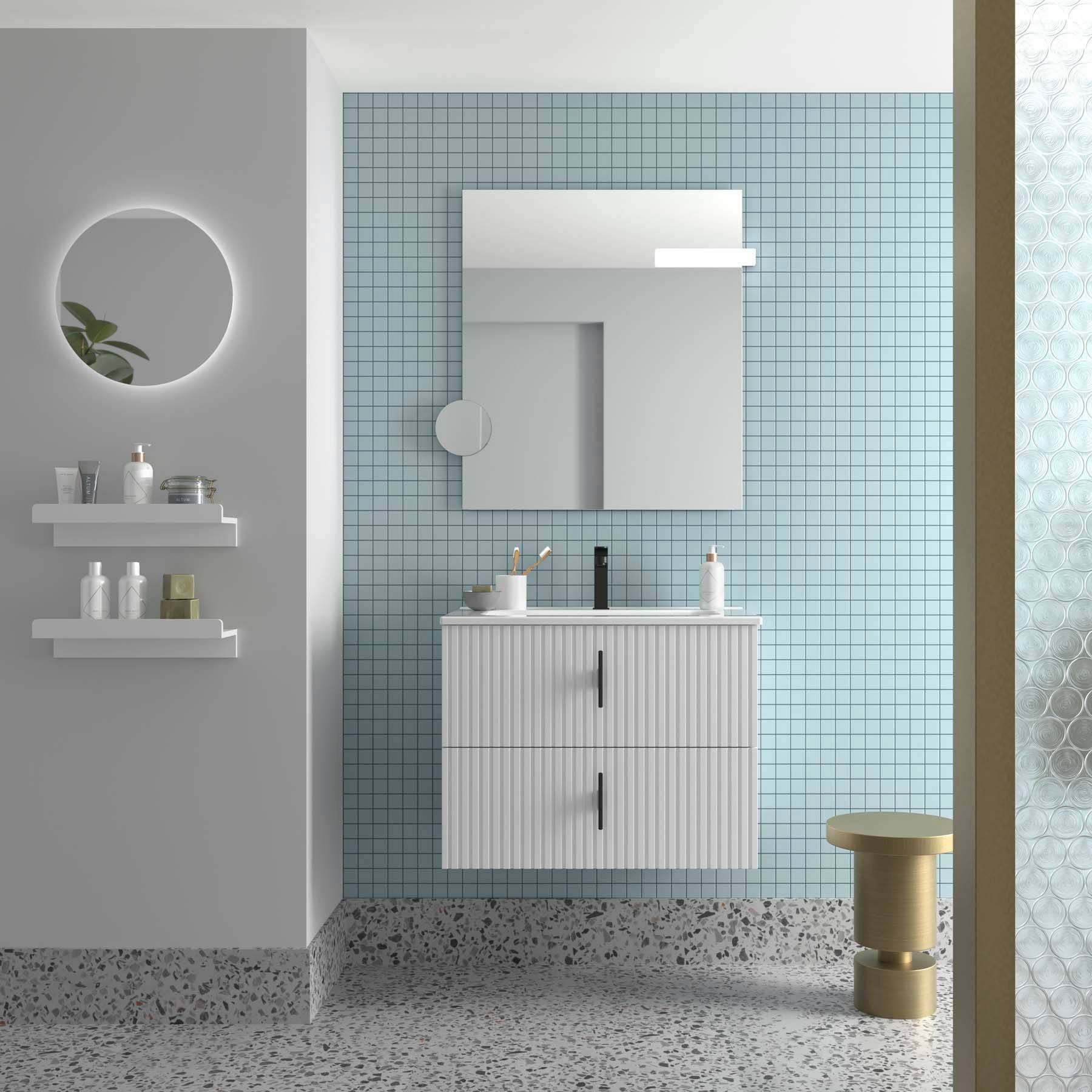 Ein modernes Badezimmer mit einem runden Spiegel, schwebenden Regalen und einem Waschtischunterschrank vor einer hellblauen gefliesten Wand. Rechts steht ein kleiner runder Tisch.