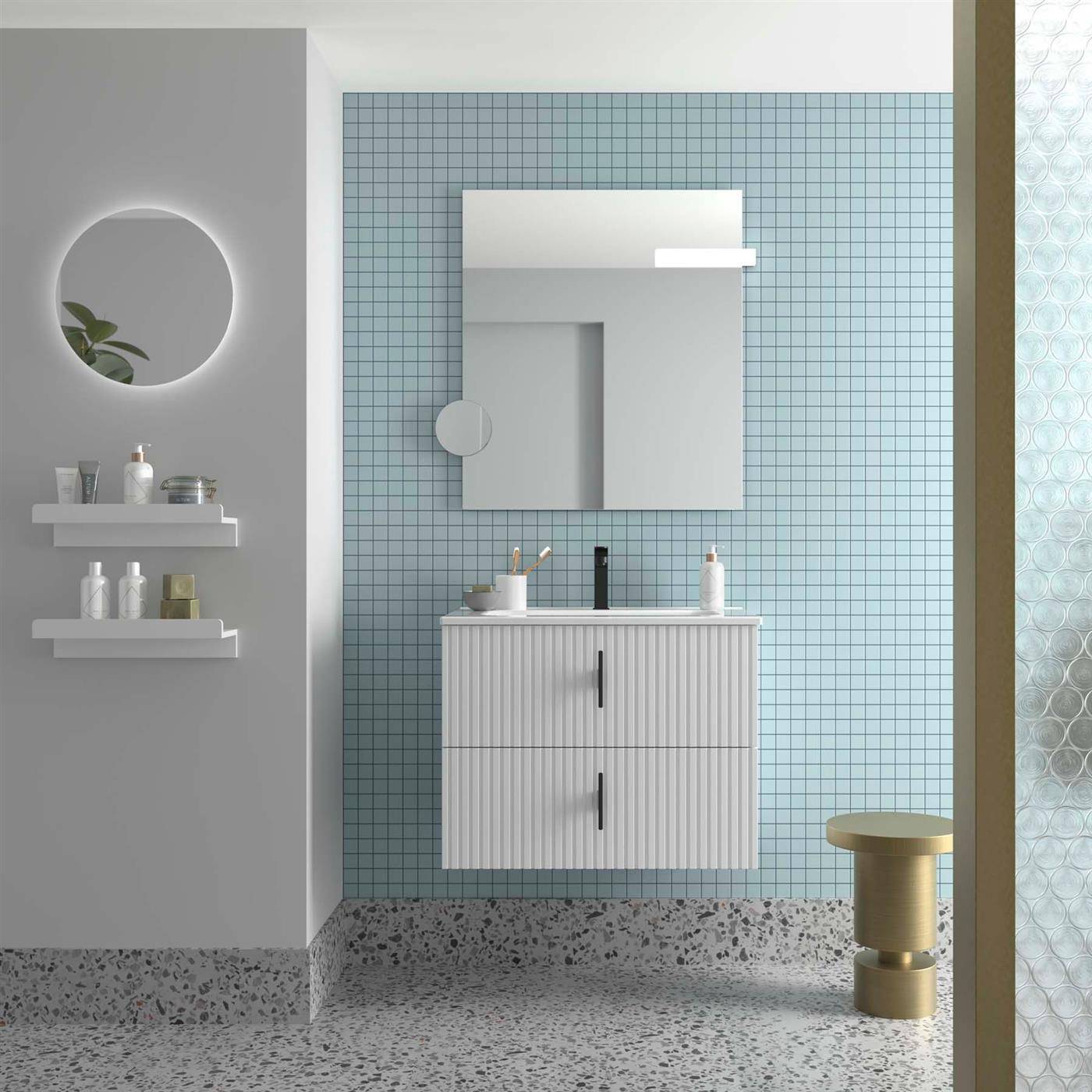 Modernes Minimalist-Badezimmer mit an der Wand montiertem Waschtisch und Spiegelschrank vor einer blaufliesigen Wand, sowie einem runden Spiegel, Regalen und einem kleinen goldfarbenen Hocker.