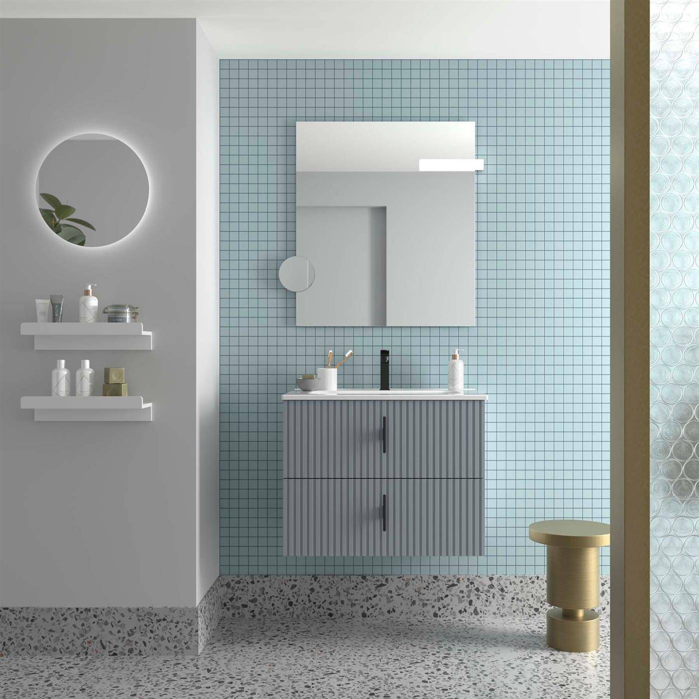 Modernes Badezimmer mit an der Wand montiertem Waschtisch, Spiegelschrank, rundem Spiegel, schwebenden Regalen und einem kleinen goldenen Hocker vor blauer Fliese.