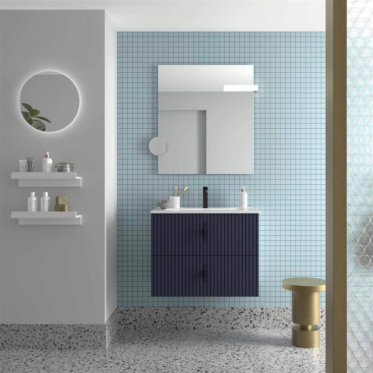 Minimales modernes Badezimmer mit an der Wand montiertem Waschtisch, Spiegelschrank, rundem Spiegel, Regalen mit Toilettenartikeln und einem kleinen goldenen Hocker auf einer gekachelten Wand.