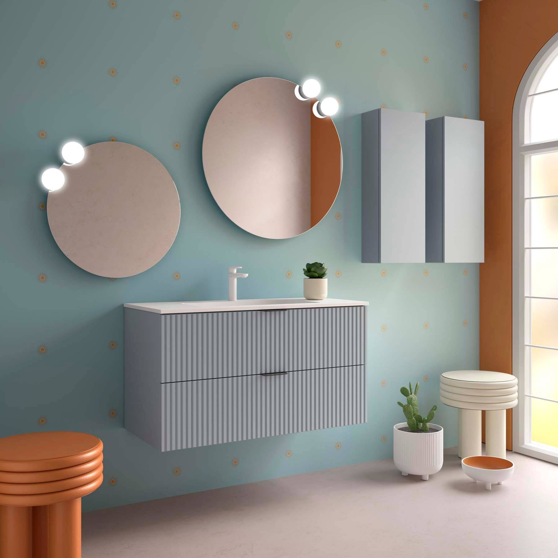 Modernes Badezimmer mit einem wandmontiertem Waschtisch, runden Spiegeln mit Beleuchtung, Topfpflanze und orangefarbenen runden Hockern in einem sanft beleuchteten Raum.