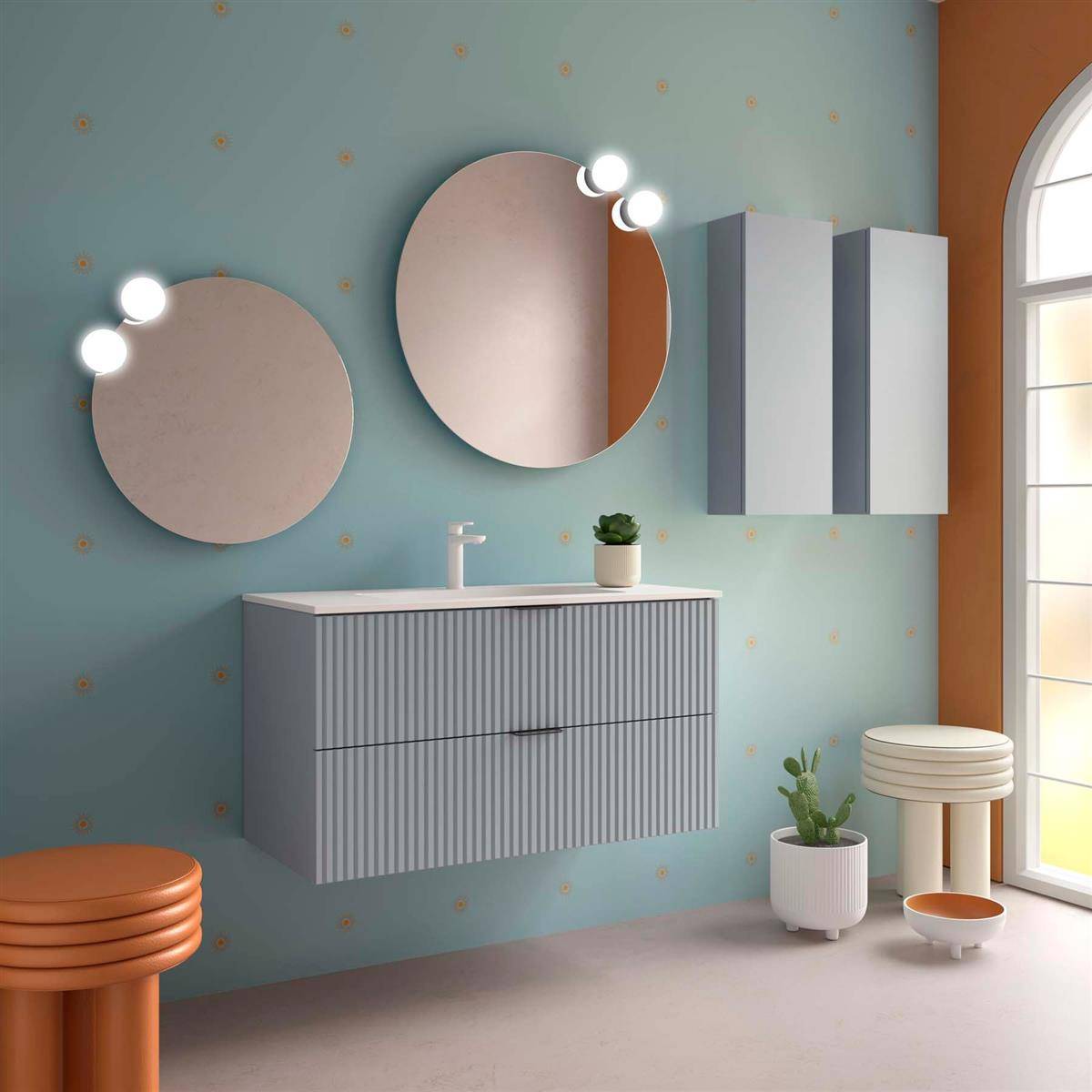 Modernes Badezimmer mit wandmontiertem gestreiftem Waschtisch, zwei runden beleuchteten Spiegeln, Schrank, Hockern und Pflanzen neben einem sonnigen Bogenfenster.