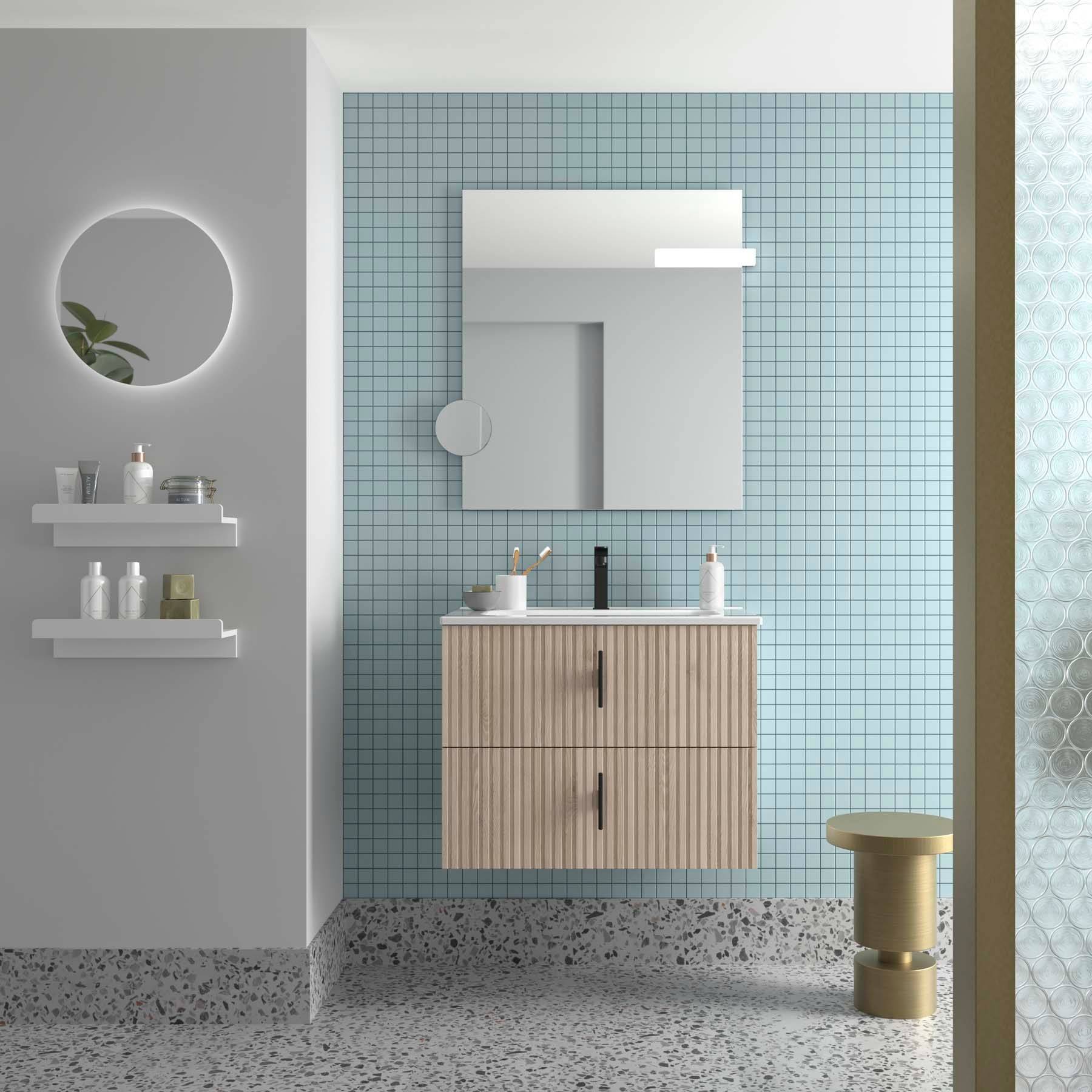 Modernes Badezimmer mit hellblauen Wandfliesen, rundem Spiegel, Holzwaschtisch mit Waschbecken und Regalen, auf denen Toilettenartikel stehen. Terrazzobodenbelag.