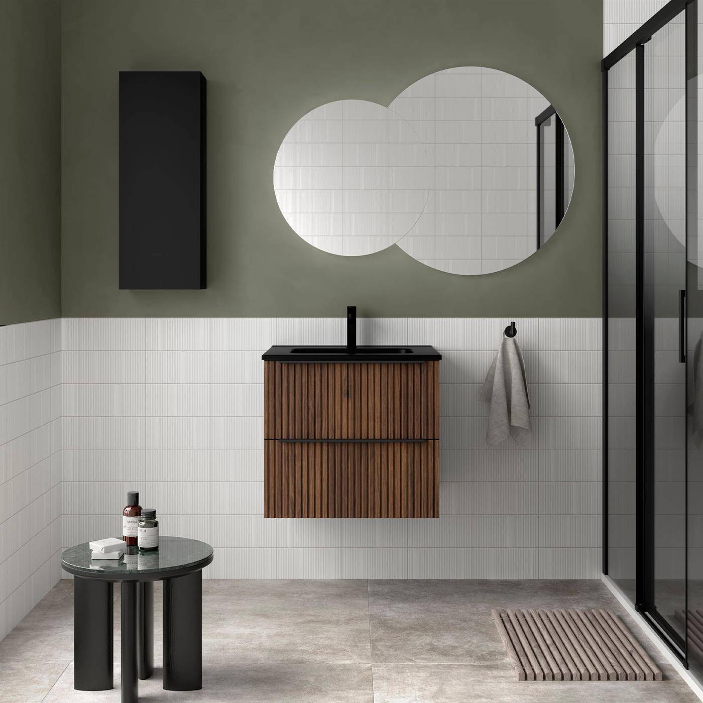 Modernes Badezimmer mit olivgrünen Wänden, weißen Fliesen, schwebendem Holzwaschtisch, rundem Doppelspiegel, schwarzer Duschkabine und kleinem Beistelltisch.