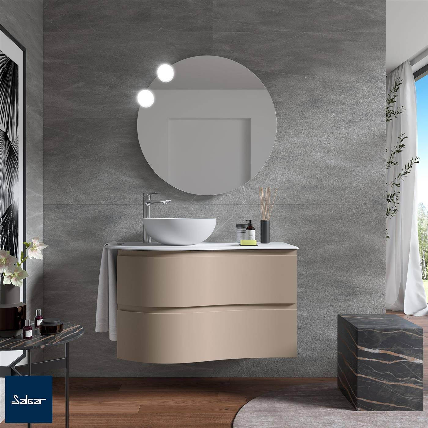 Modernes Badezimmerwaschtisch mit rundem Spiegel, Aufsatzwaschbecken und wandmontiertem Wasserhahn vor einer grau strukturierten Wand, mit Fensterlicht und Marmor-Akzentuierhocker.