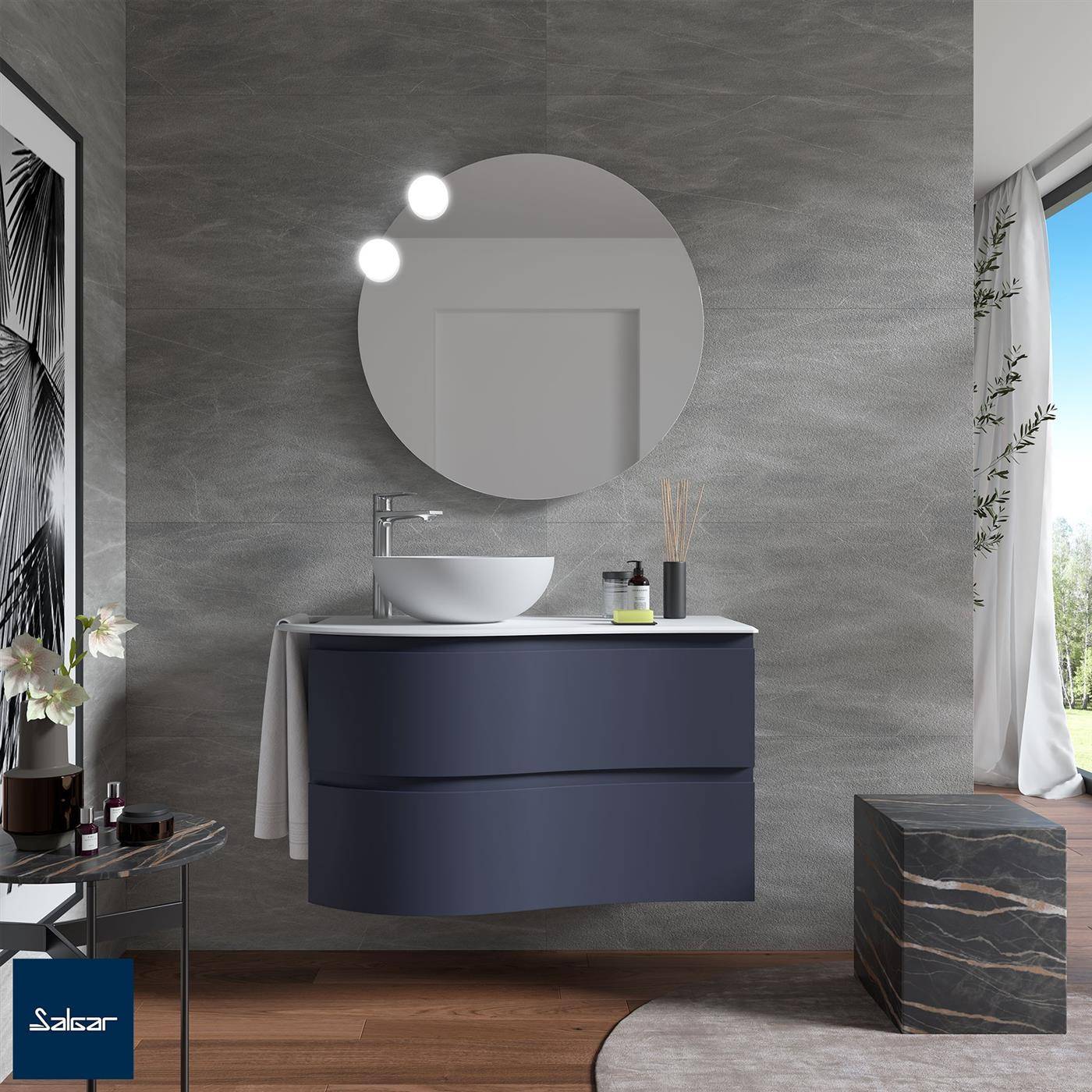 Modernes Badezimmer mit schwebendem dunkelblauem Waschtisch, rundem Spiegel, Aufsatzwaschbecken und strukturierter grauer Wand; Marmorschemel, Holzboden und Fenster mit transparentem Vorhang.