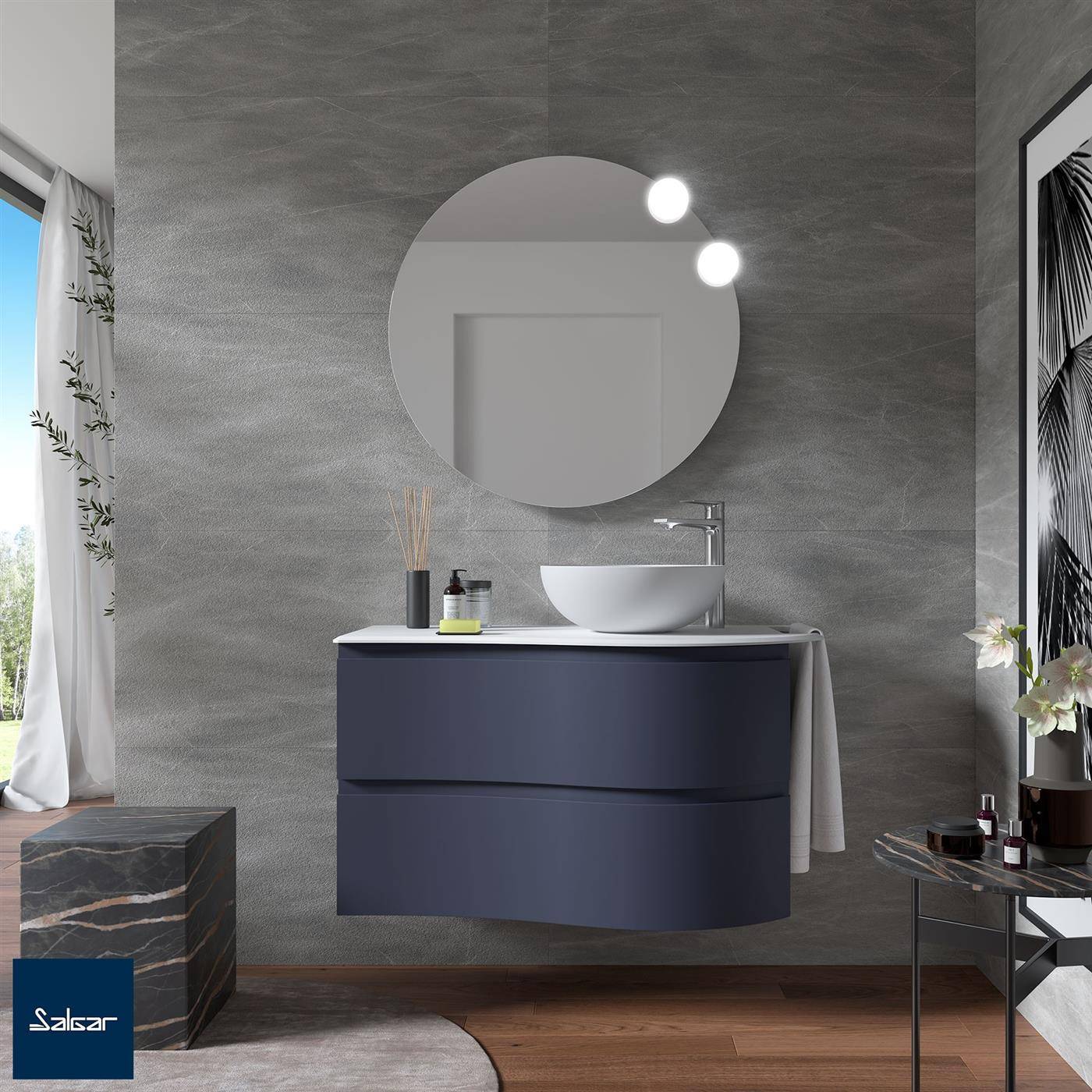 Modernes Badezimmer mit an der Wand montiertem marineblauen Waschtisch, rundem Spiegel, Aufsatzwaschbecken und grauer strukturierter Wand, mit Fenster, Beistelltisch und Hocker.