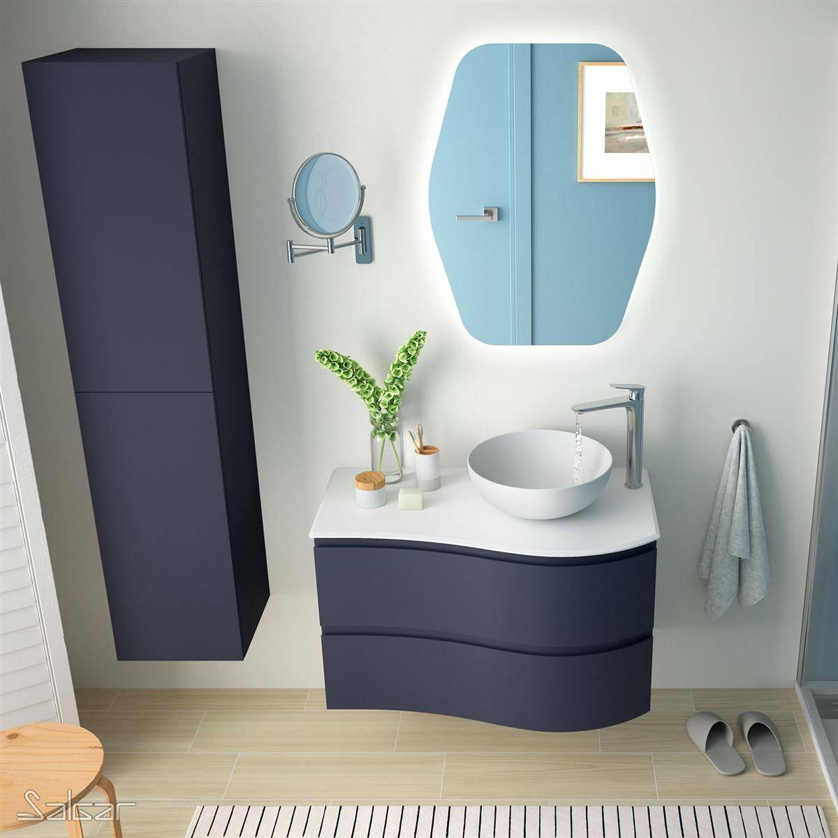 Modernes Badezimmer mit dunkelblauem Schrank, weißem Aufsatzwaschbecken, blaugerahmtem Spiegel, Wandschrank, Handtuch und Hausschuhen auf hellem Holzboden.