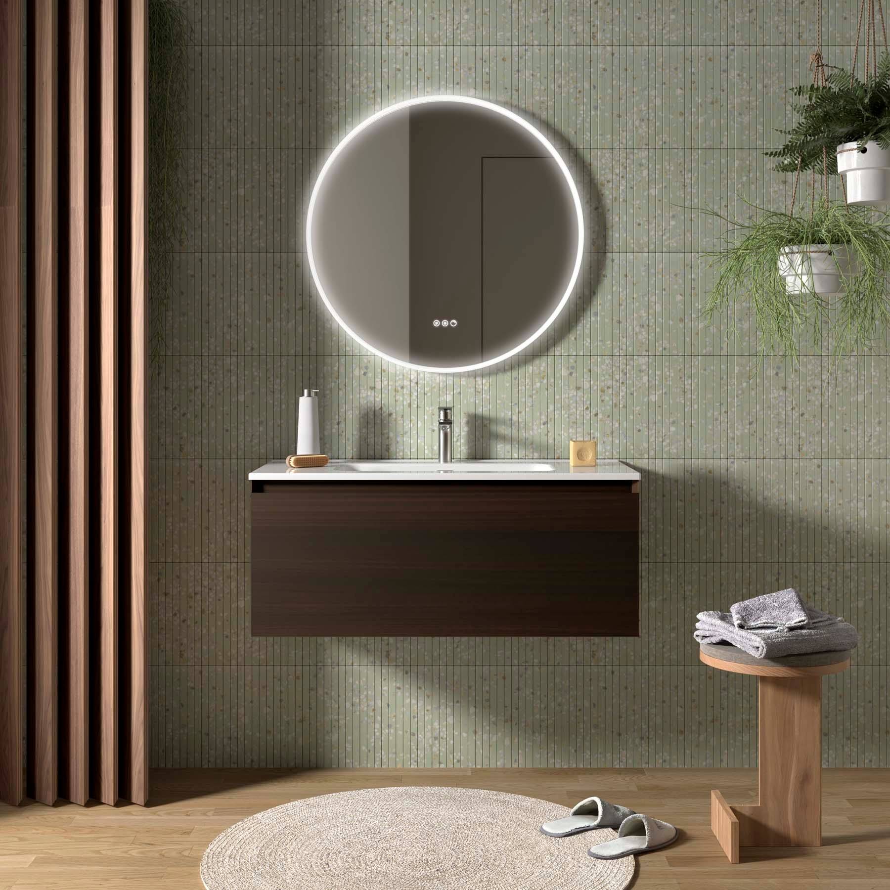 Modernes Badezimmer mit rundem, beleuchtetem Spiegel, Waschtisch aus dunklem Holz und elegantem Wasserhahn. Neutrale Töne und minimale Dekoration schaffen eine ruhige Atmosphäre.